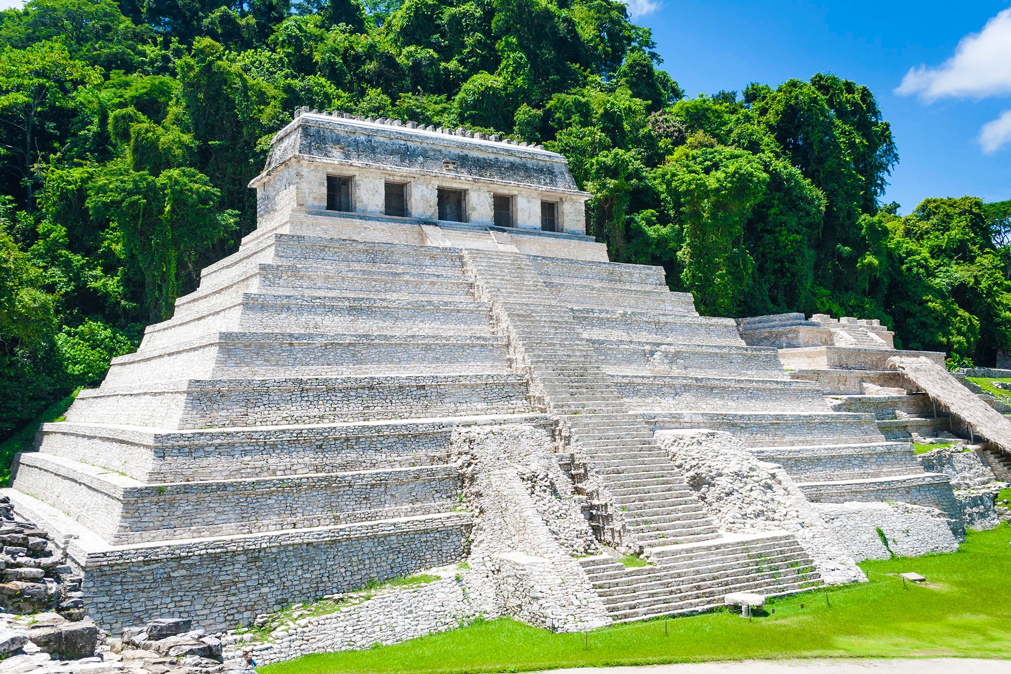 A stepped stone Maya pyramid with a temple on top, surrounded by rainforest