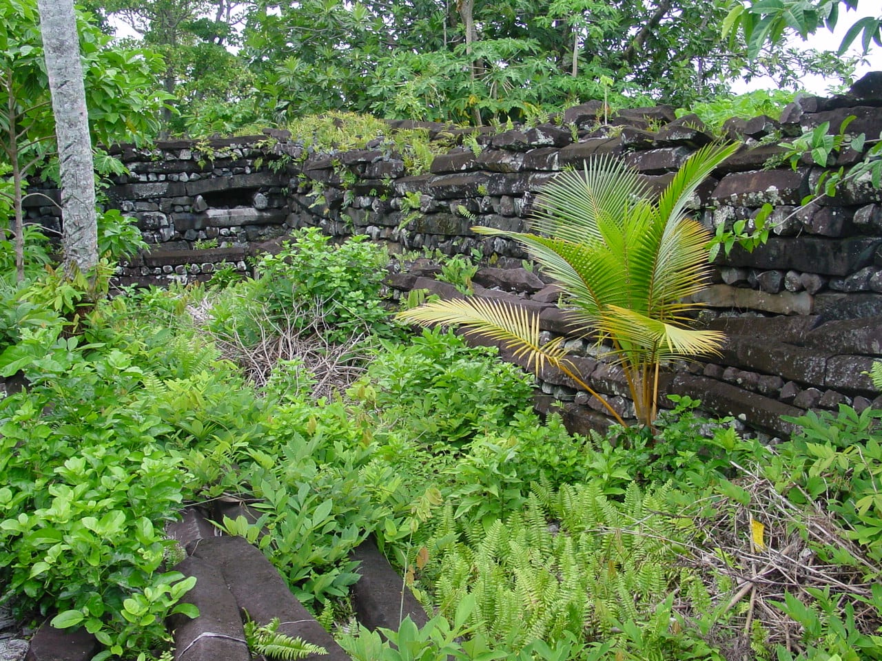 Massive stacked basalt log-shaped stones forming ancient ruined walls over water