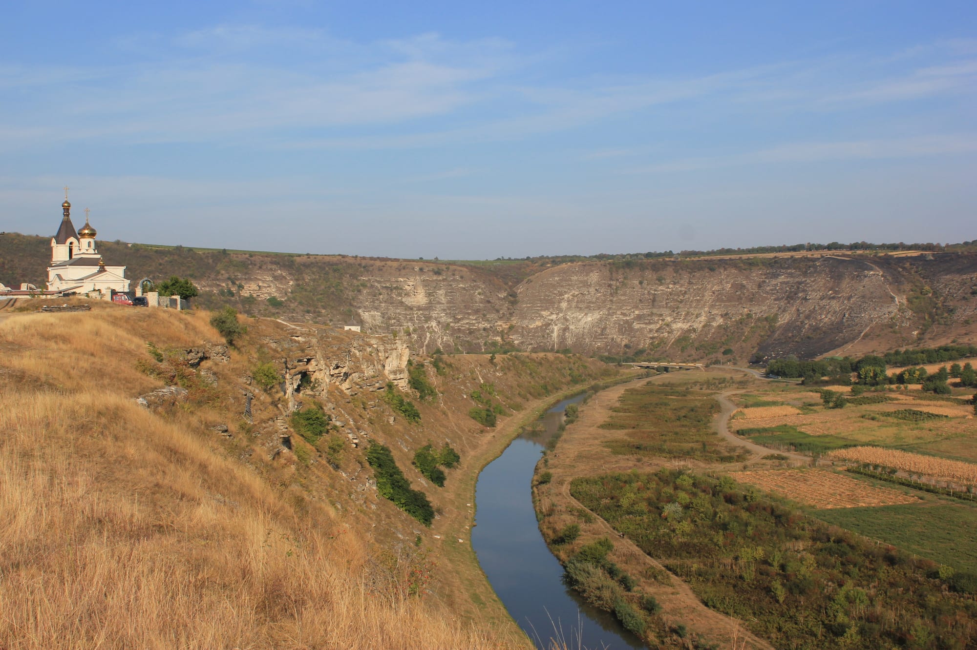 A small church perched on a dramatic limestone cliff above a river bend