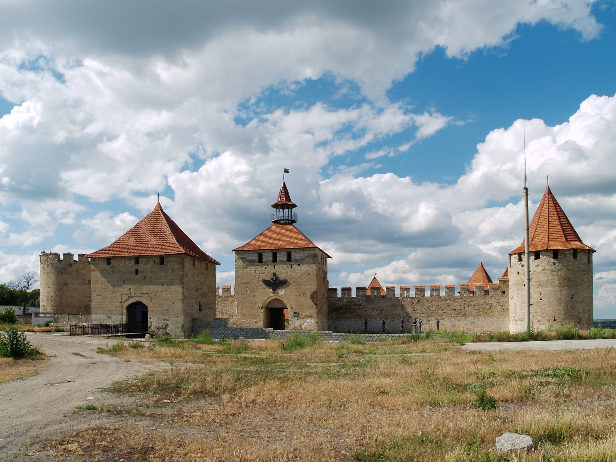 Thick medieval stone fortress walls and a tower beside a wide river