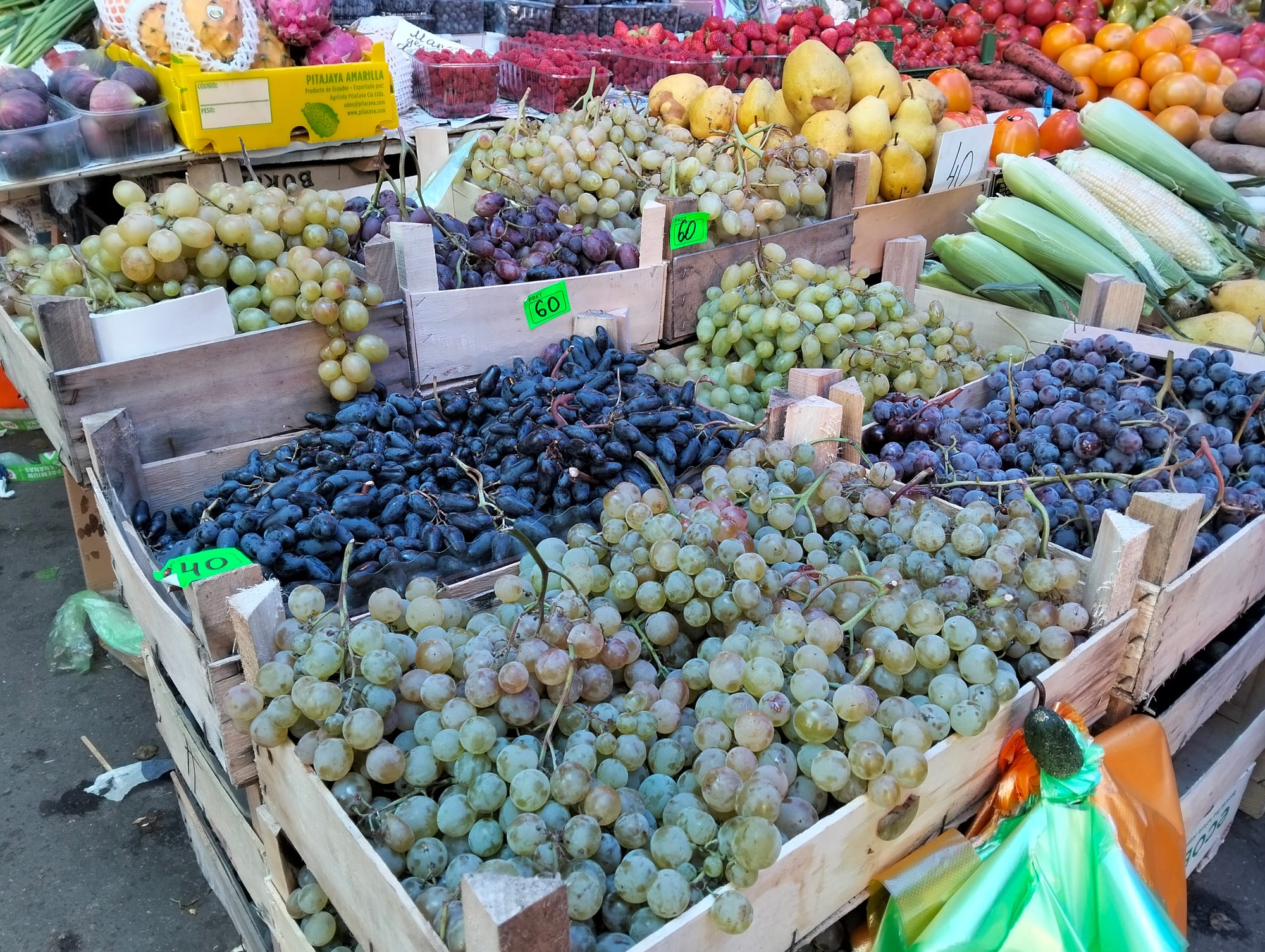 A market stall with several varieties of grapes on display