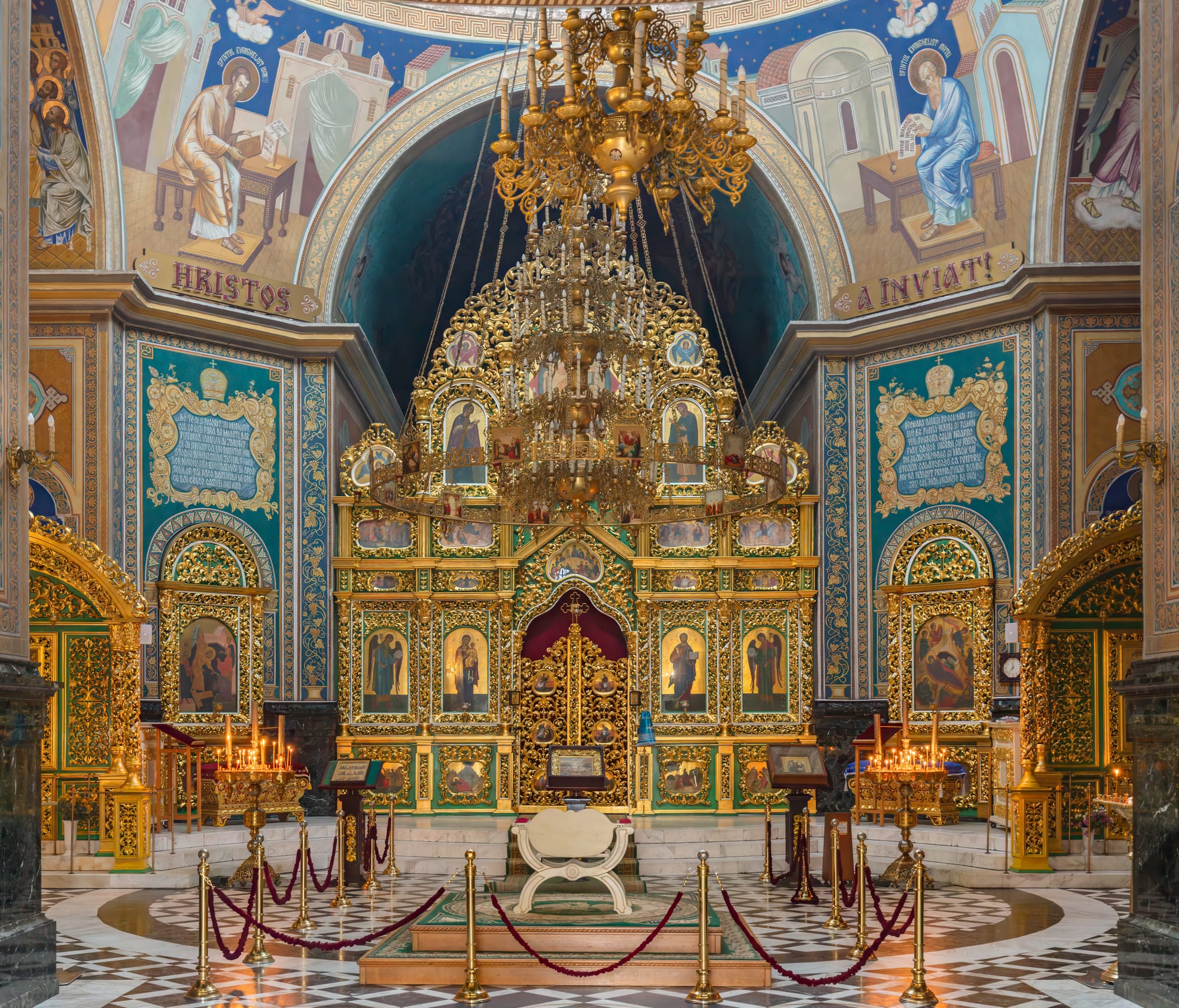 A white neoclassical Orthodox cathedral with a green dome and a separate bell tower in a city park
