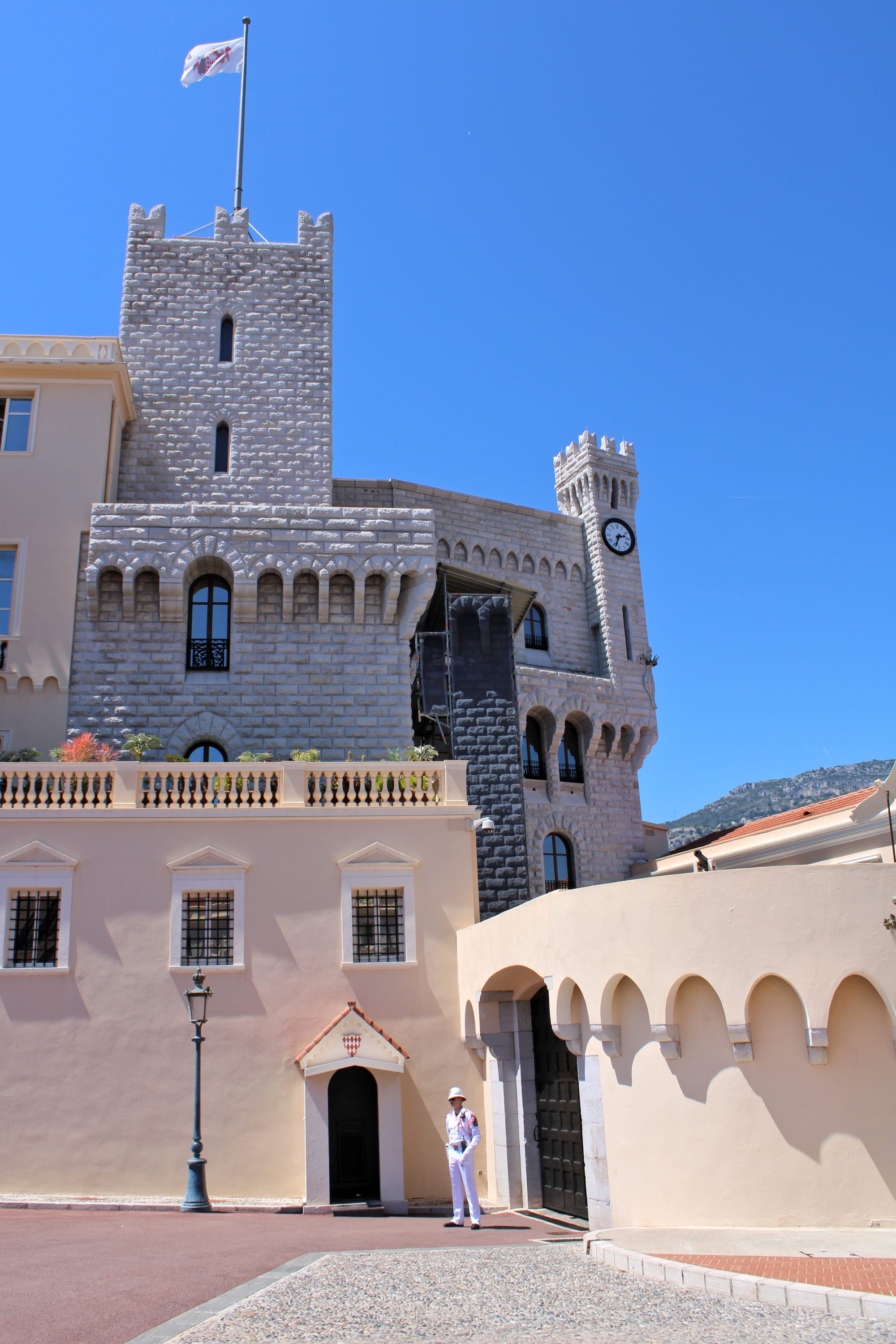 A cream-coloured palace with red-brick towers on a rocky headland above the sea