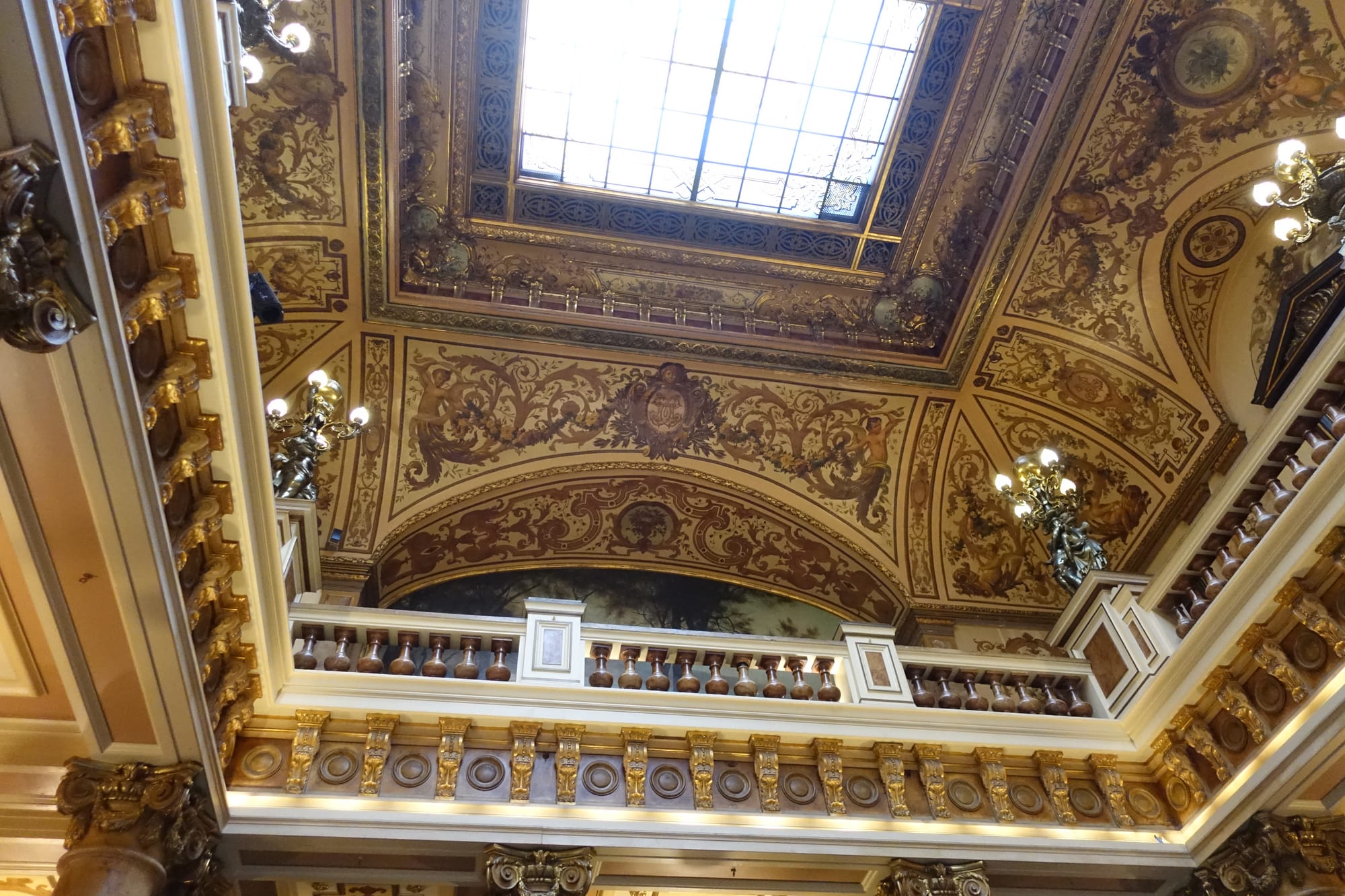 An opulent Belle Époque gilded ceiling and balustrade with ornate chandeliers