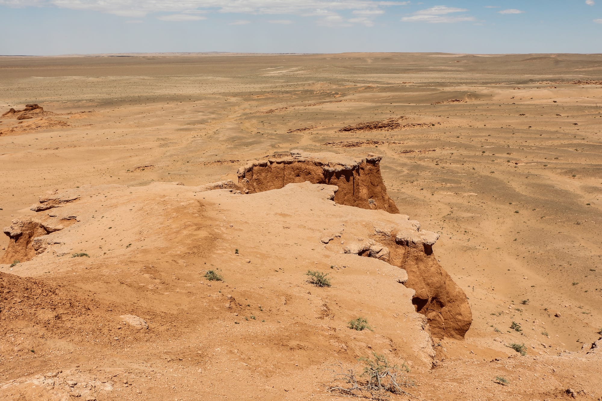 Eroded red-orange rock cliffs and gullies in the desert at sunset