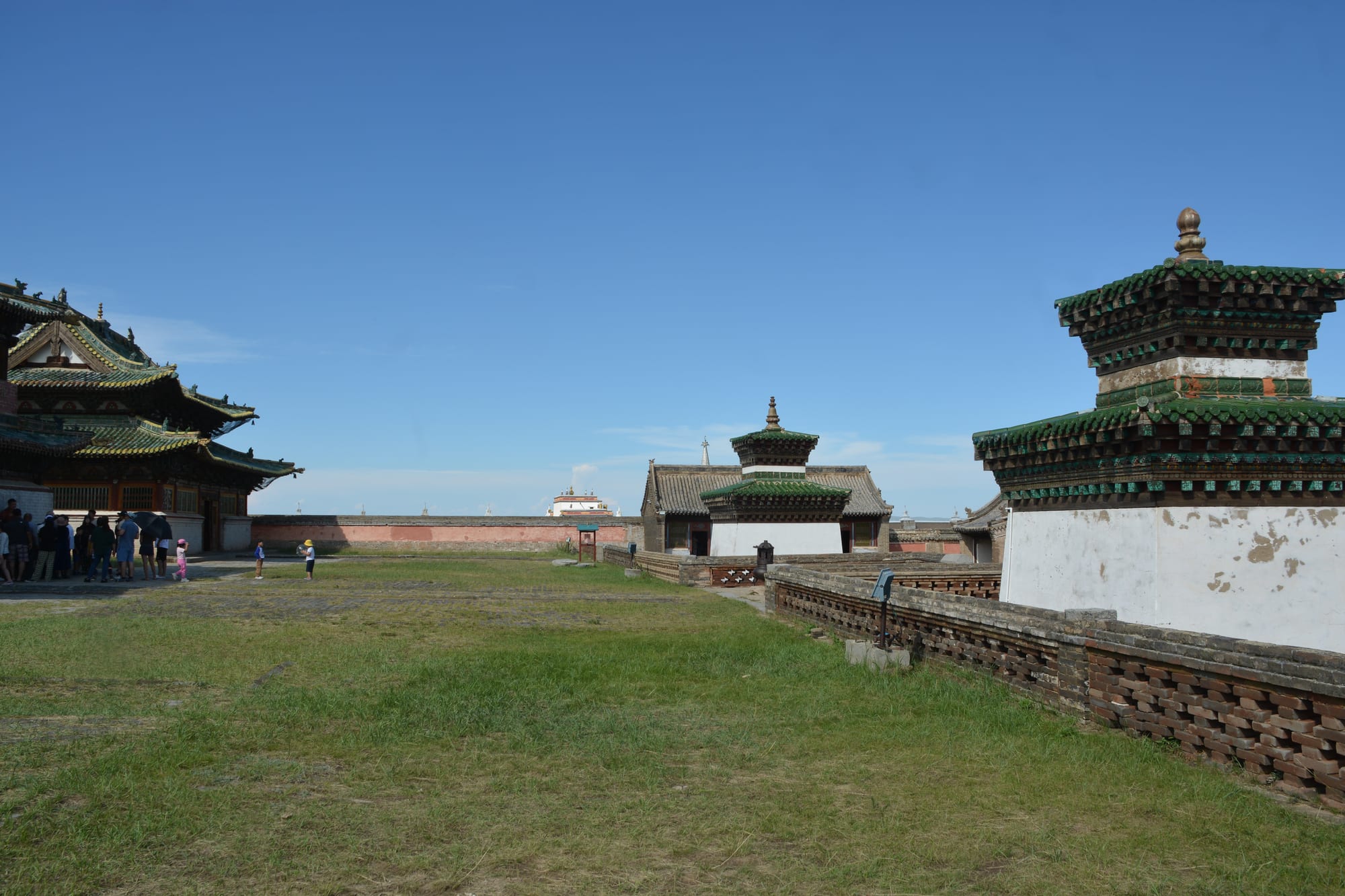 A walled Buddhist monastery of white stupas and temple roofs on the open Mongolian plain