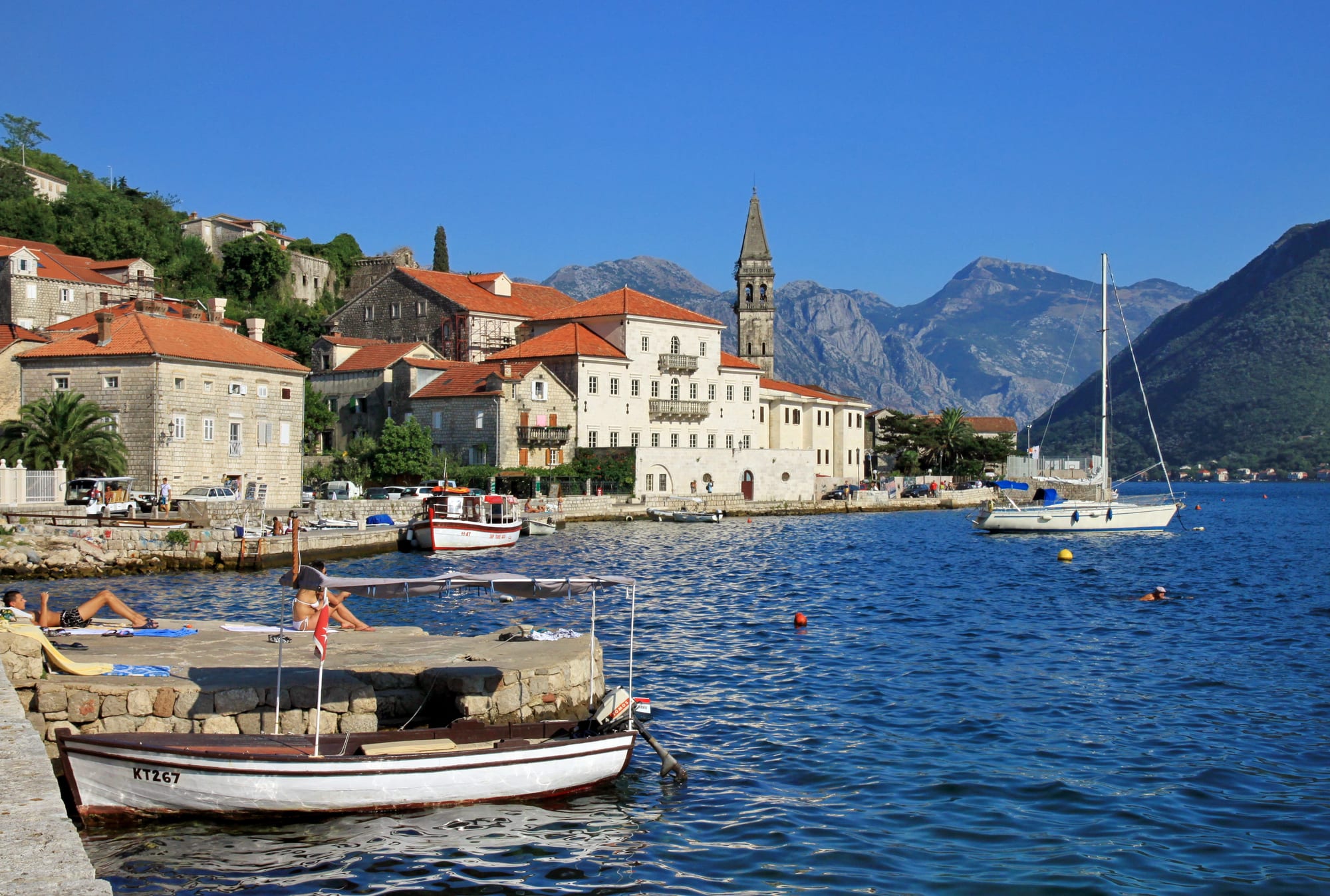 A row of stone Venetian palaces along a bay shore, with a small church-topped island offshore