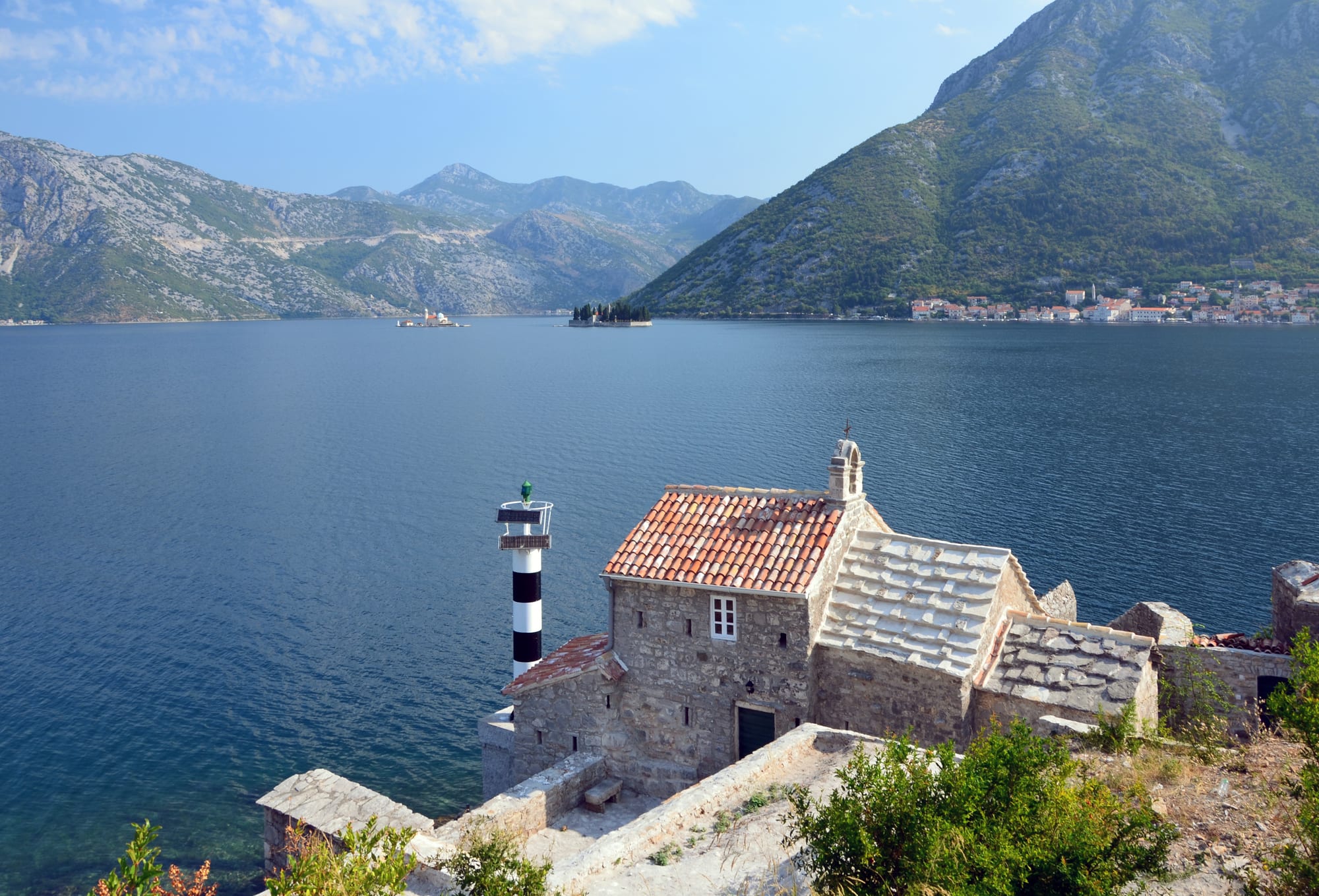 A winding bay of deep blue water ringed by steep mountains and small towns