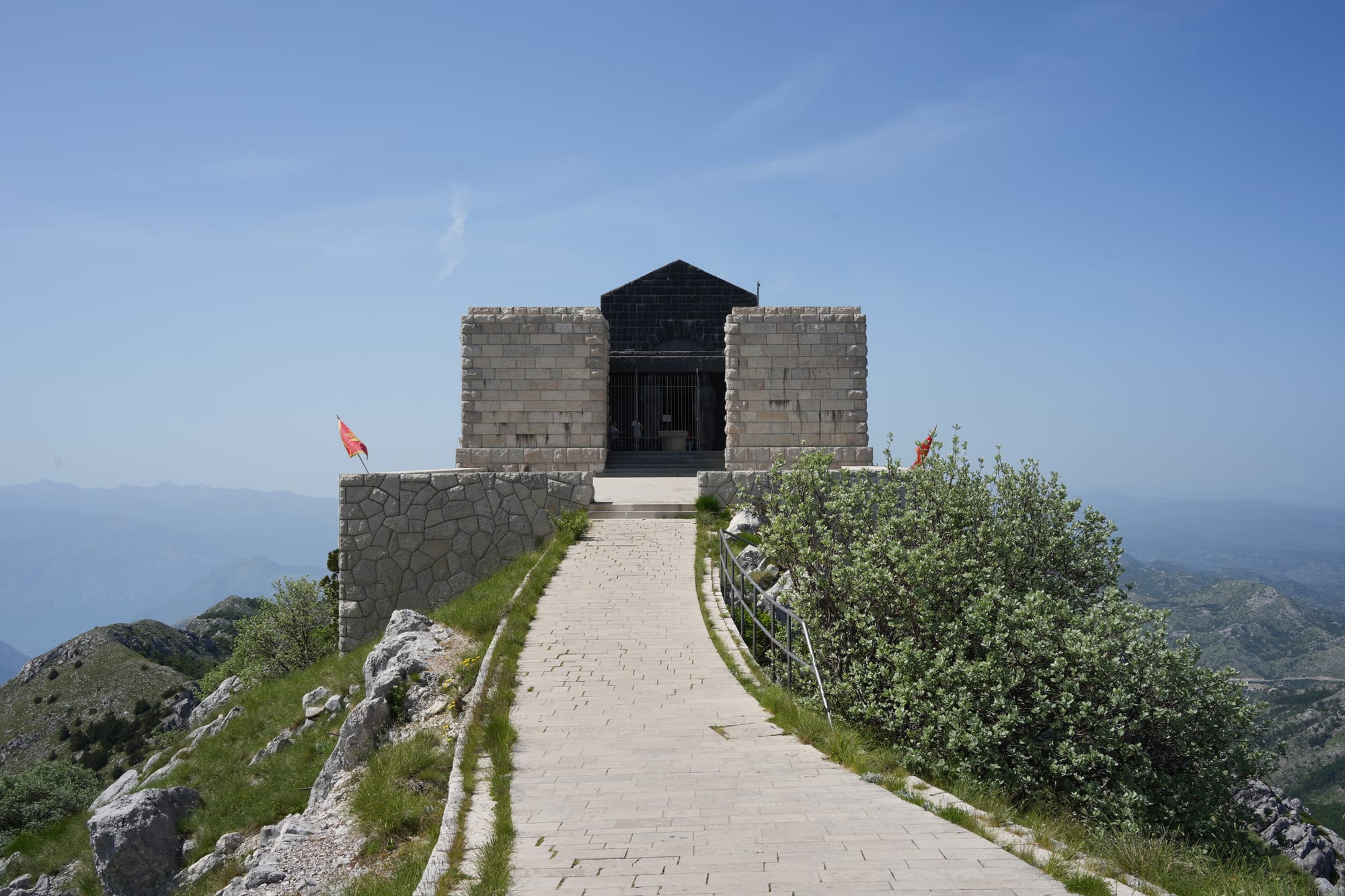 A stark stone mausoleum on a high mountain summit, wrapped in cloud