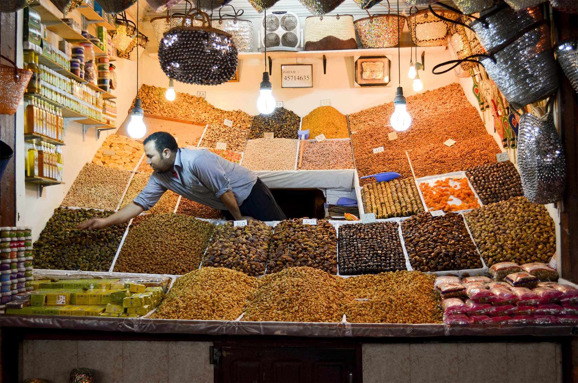 A market stall piled high with dried fruit, nuts and dates, with a vendor arranging the produce