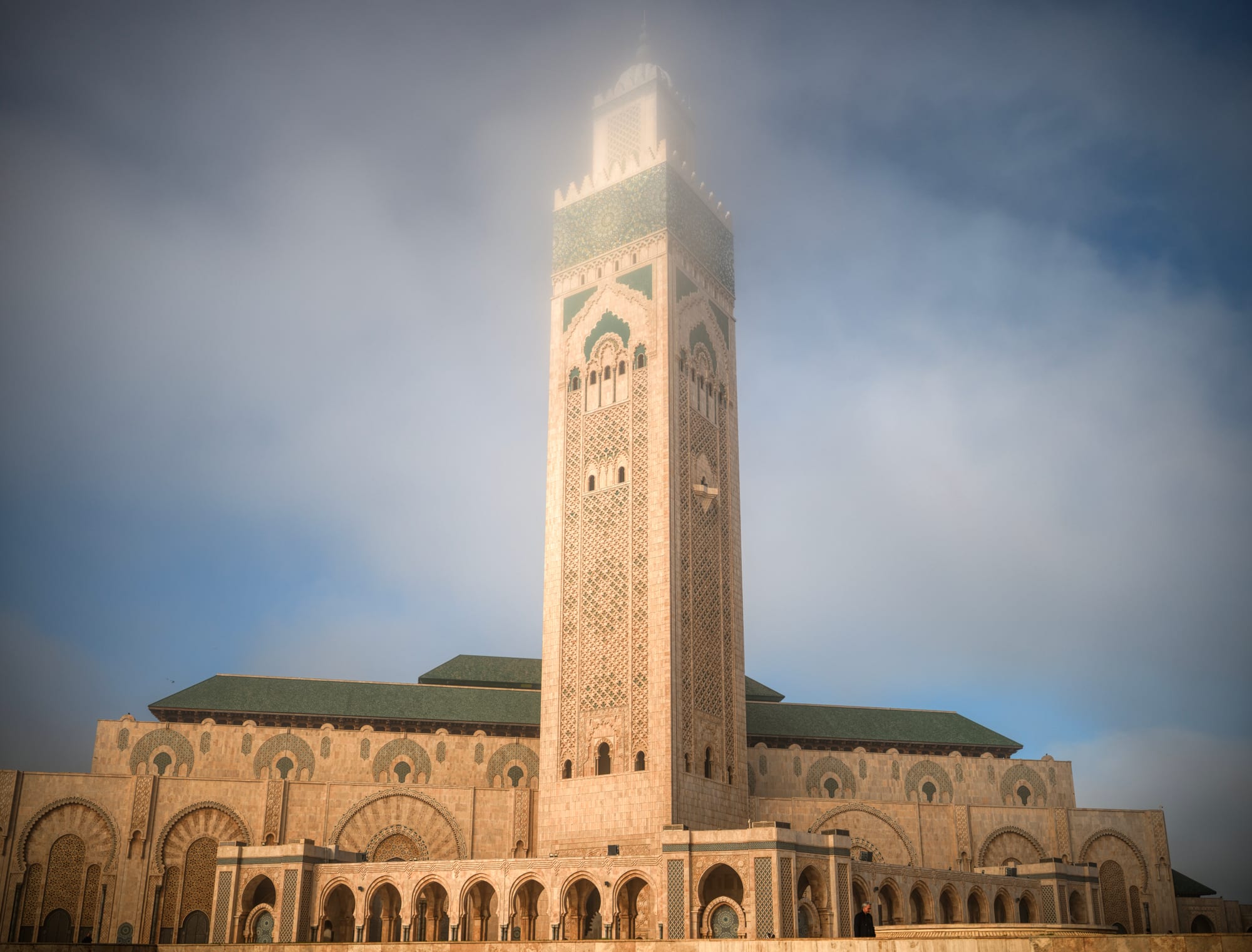A vast mosque with an enormous minaret standing on the edge of the ocean