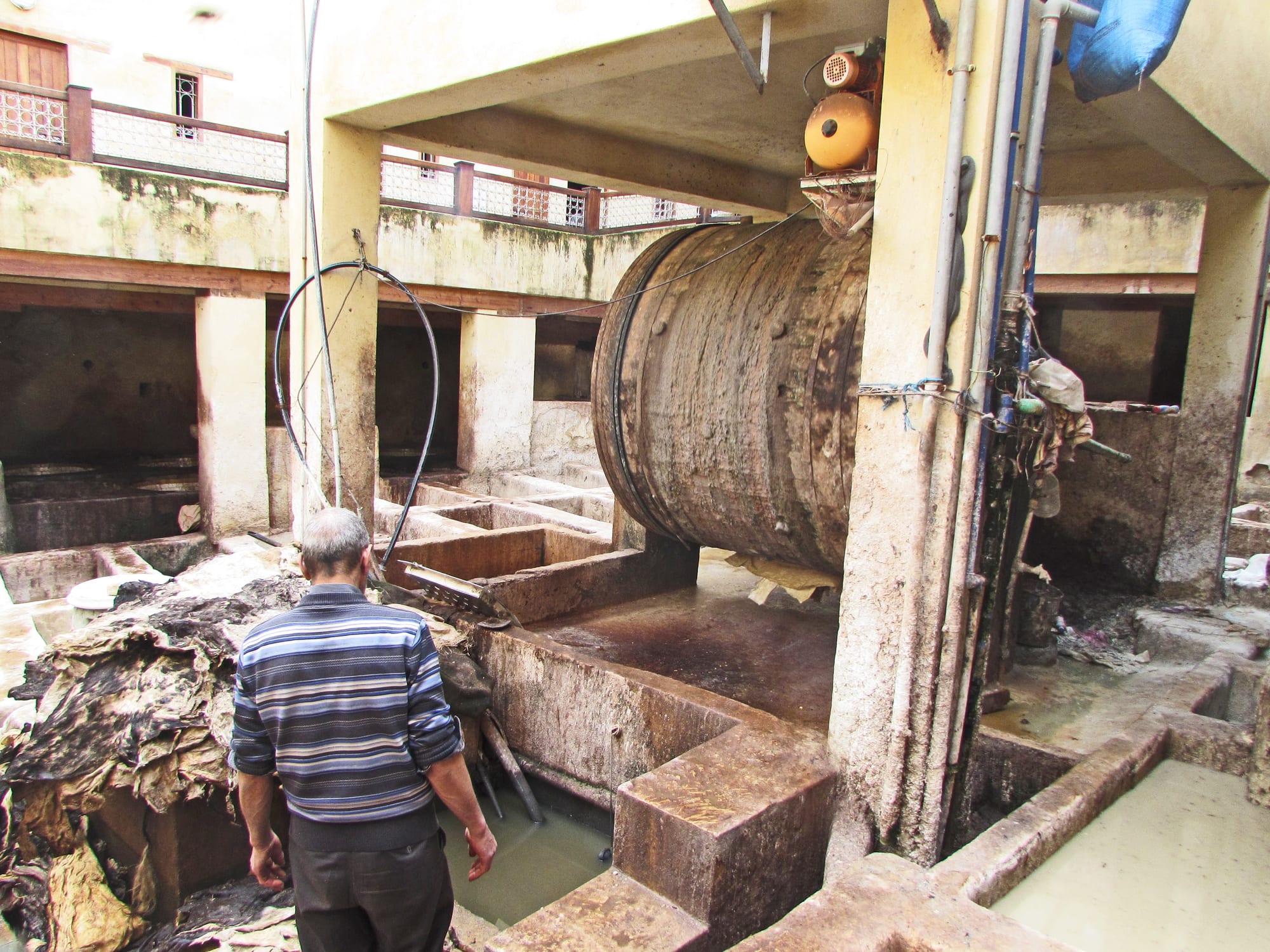 Rows of round stone dye vats filled with colourful dyes, workers treating hides