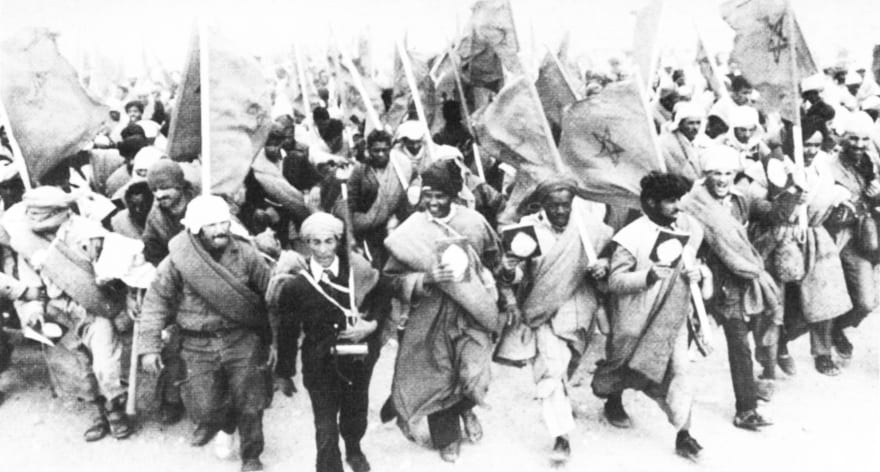 A vast column of Moroccan marchers carrying flags and Qurans crossing the desert in 1975