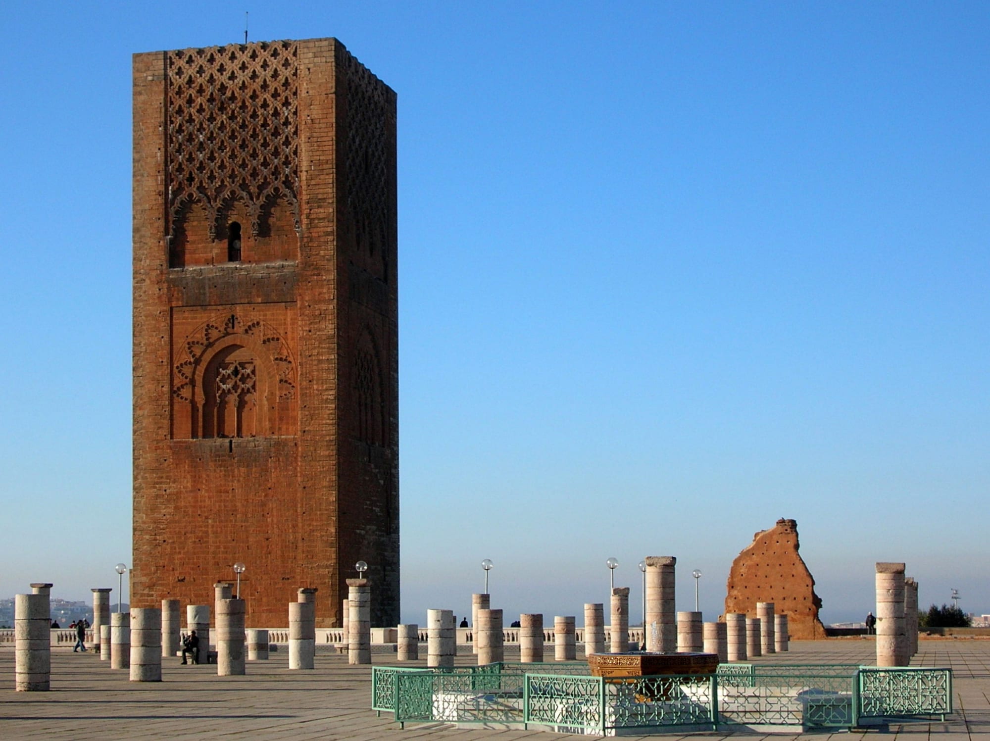 A large unfinished square stone minaret surrounded by rows of stone column stumps in Rabat