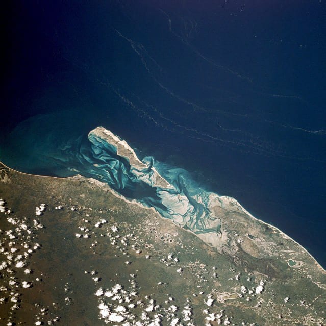 A dune-backed tropical island with white sand and turquoise water