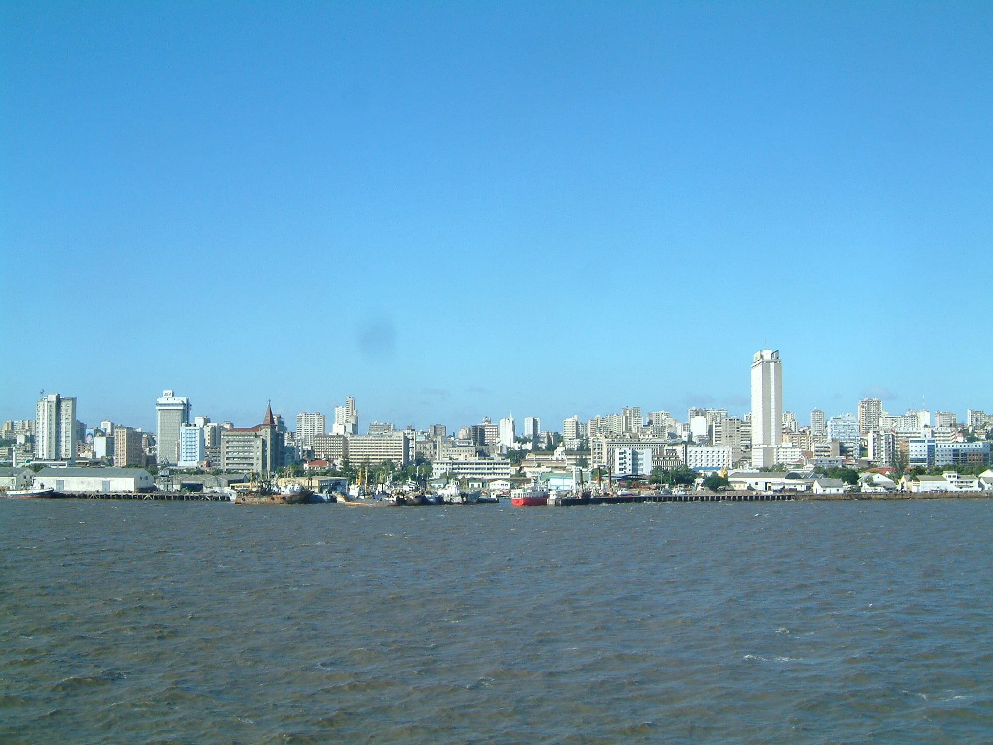 A city skyline seen from the sea, with a harbour and container port in the foreground