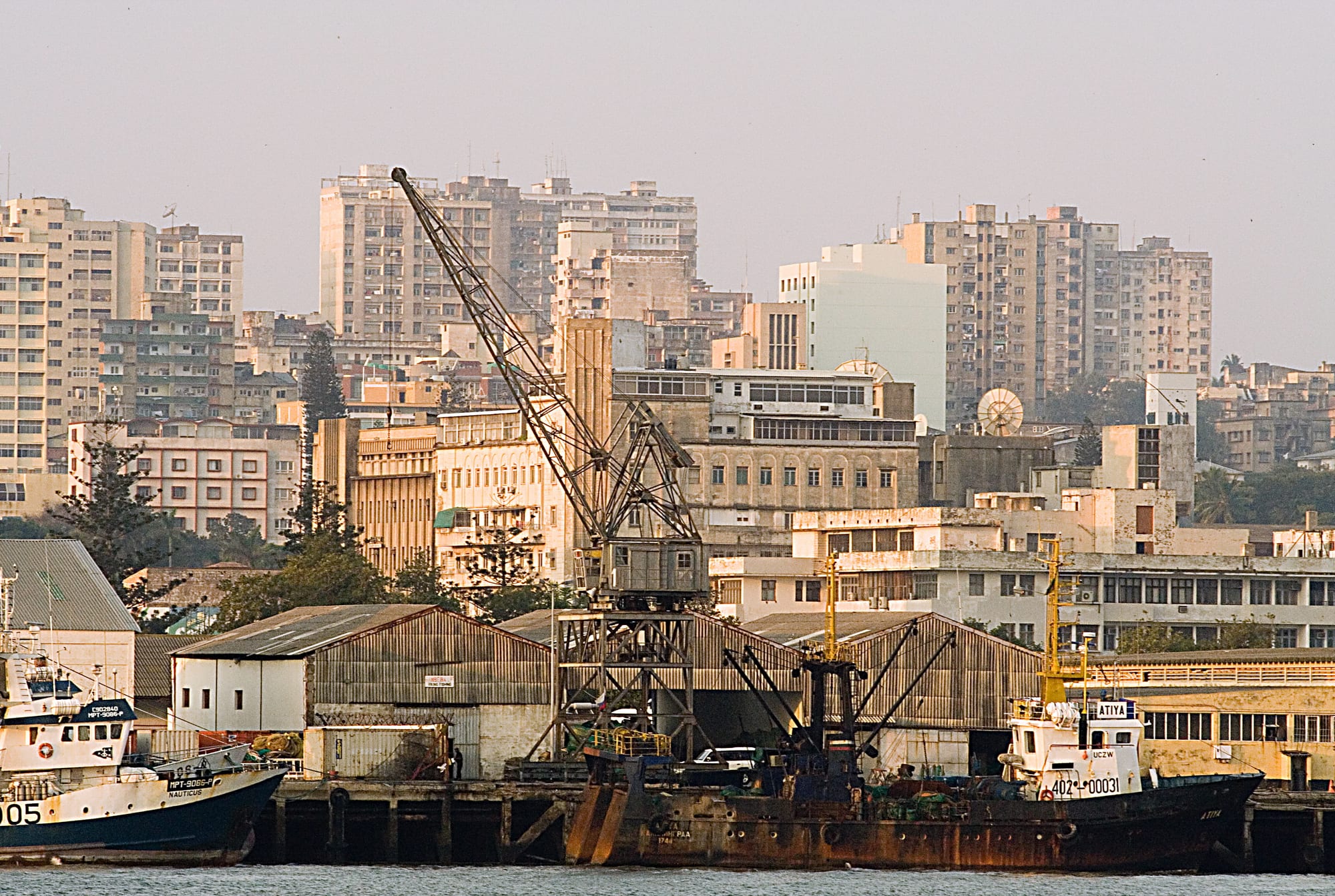 A coastal city skyline with modern and colonial-era buildings along the water
