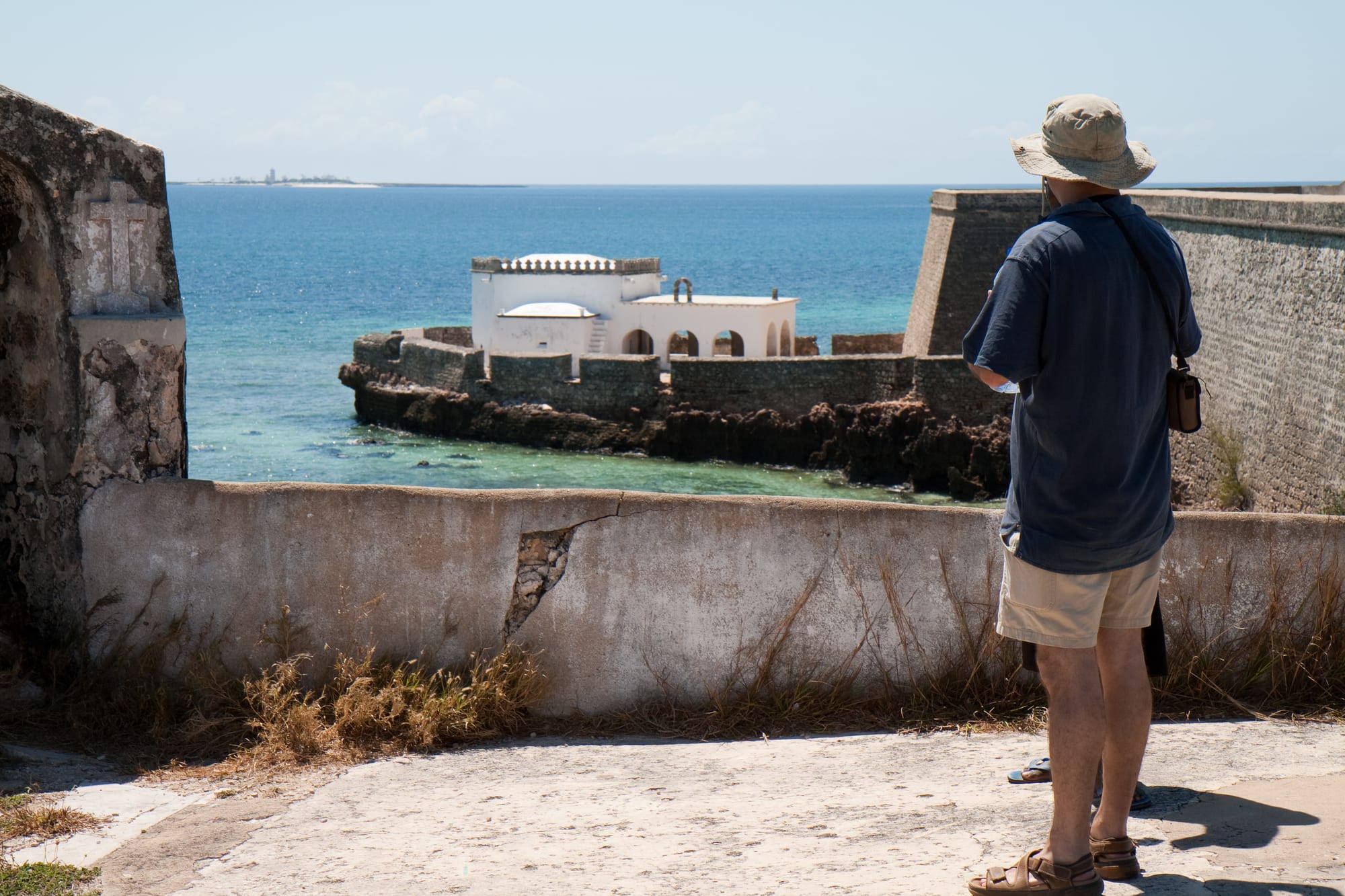 A weathered stone town of Portuguese colonial buildings and a whitewashed church on a low coral island