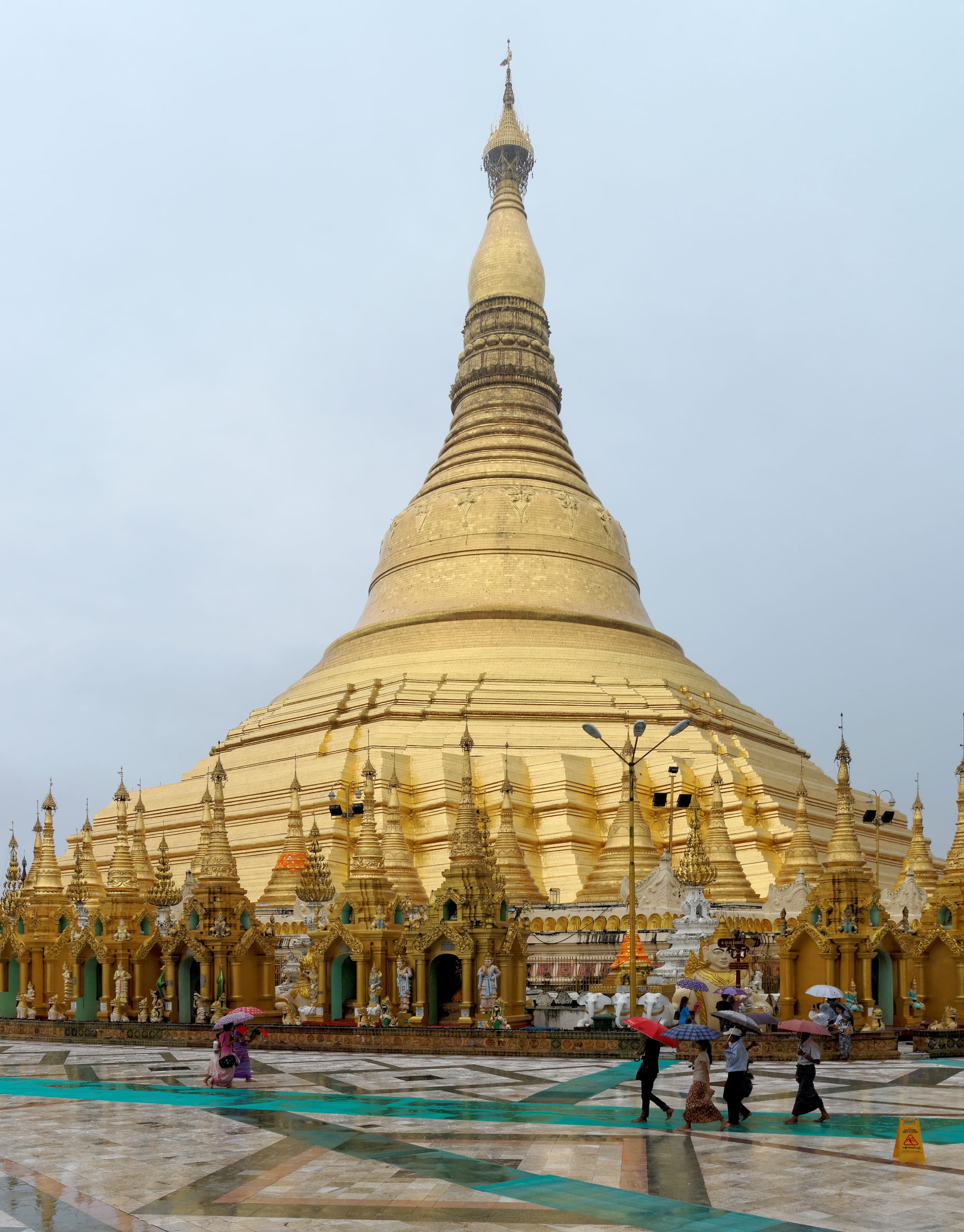 A vast golden stupa surrounded by smaller gilded temples at sunset