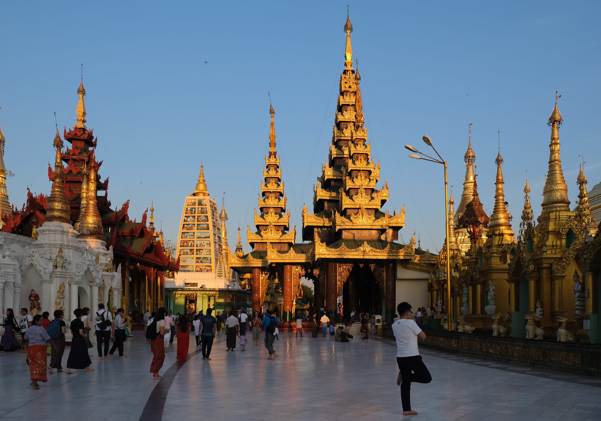 Pilgrims walking barefoot around a huge golden stupa complex at dusk