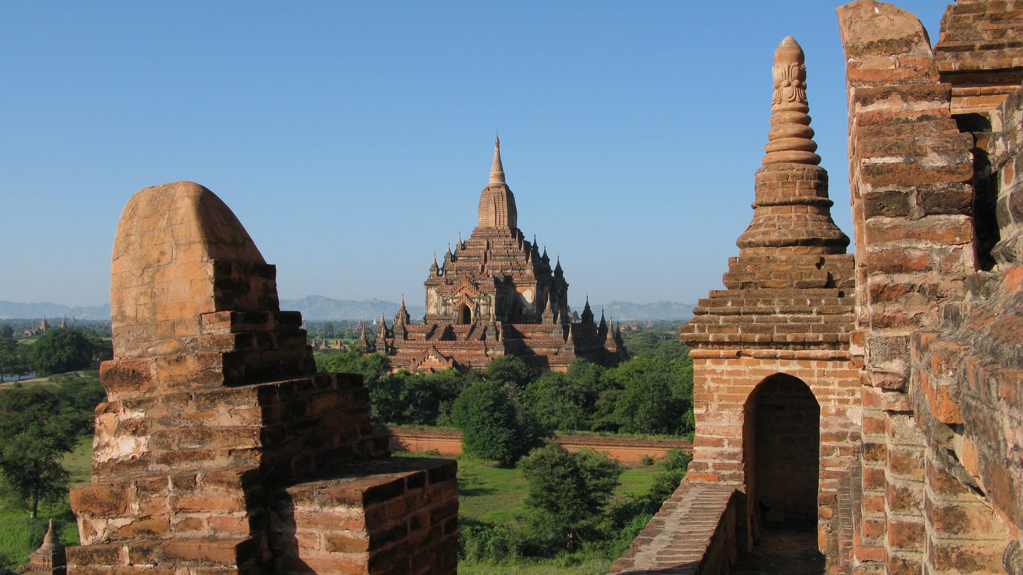 Hundreds of brick temples and stupas of varying sizes rising from a hazy plain at sunrise