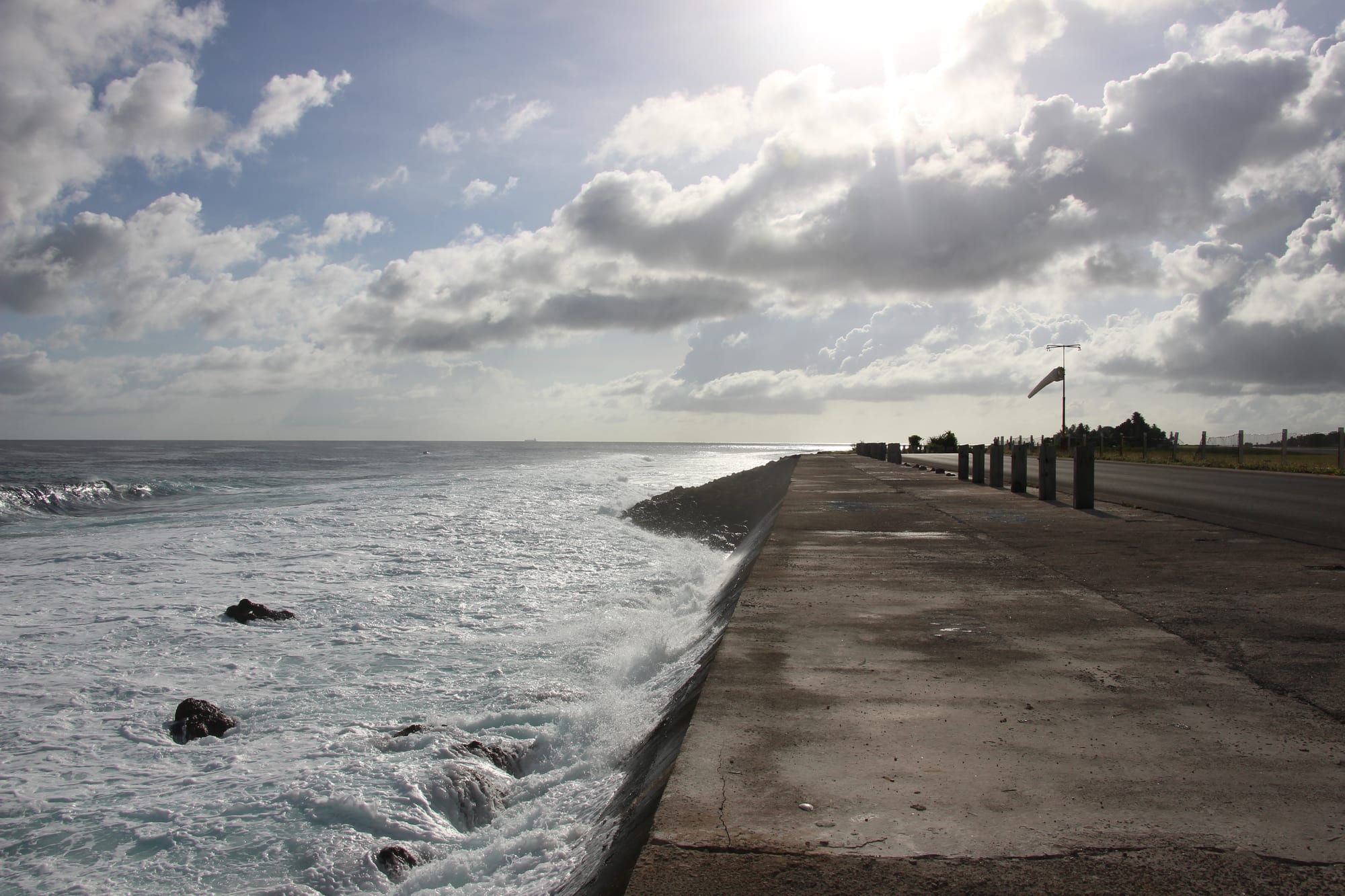 Ocean waves breaking against a sea wall at the end of an airport runway