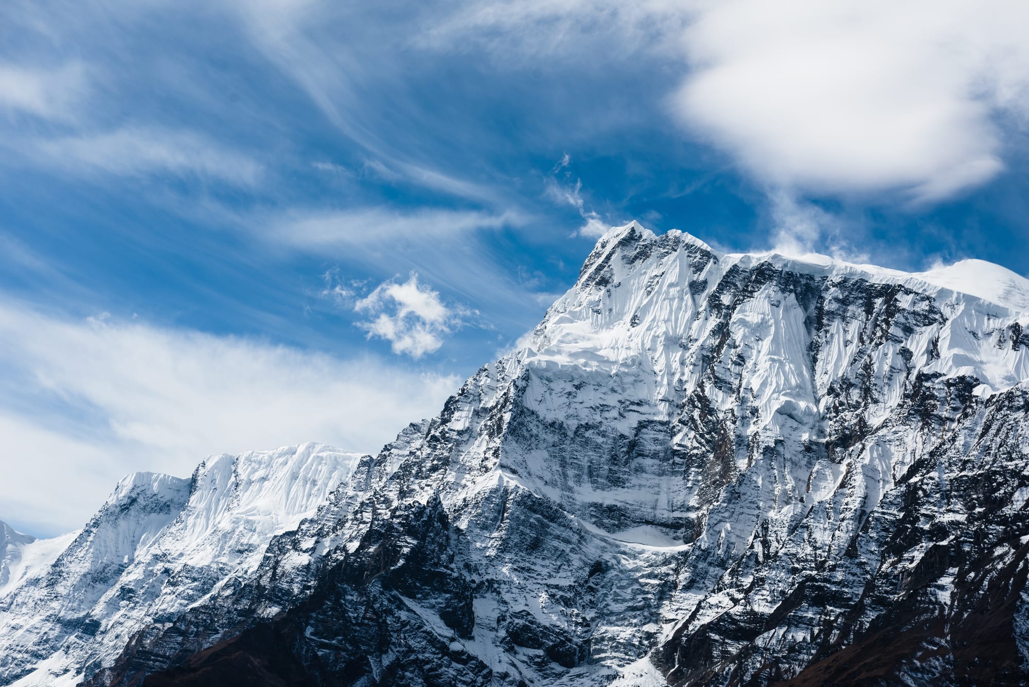 A trail through high mountain terrain with a huge snow peak towering above