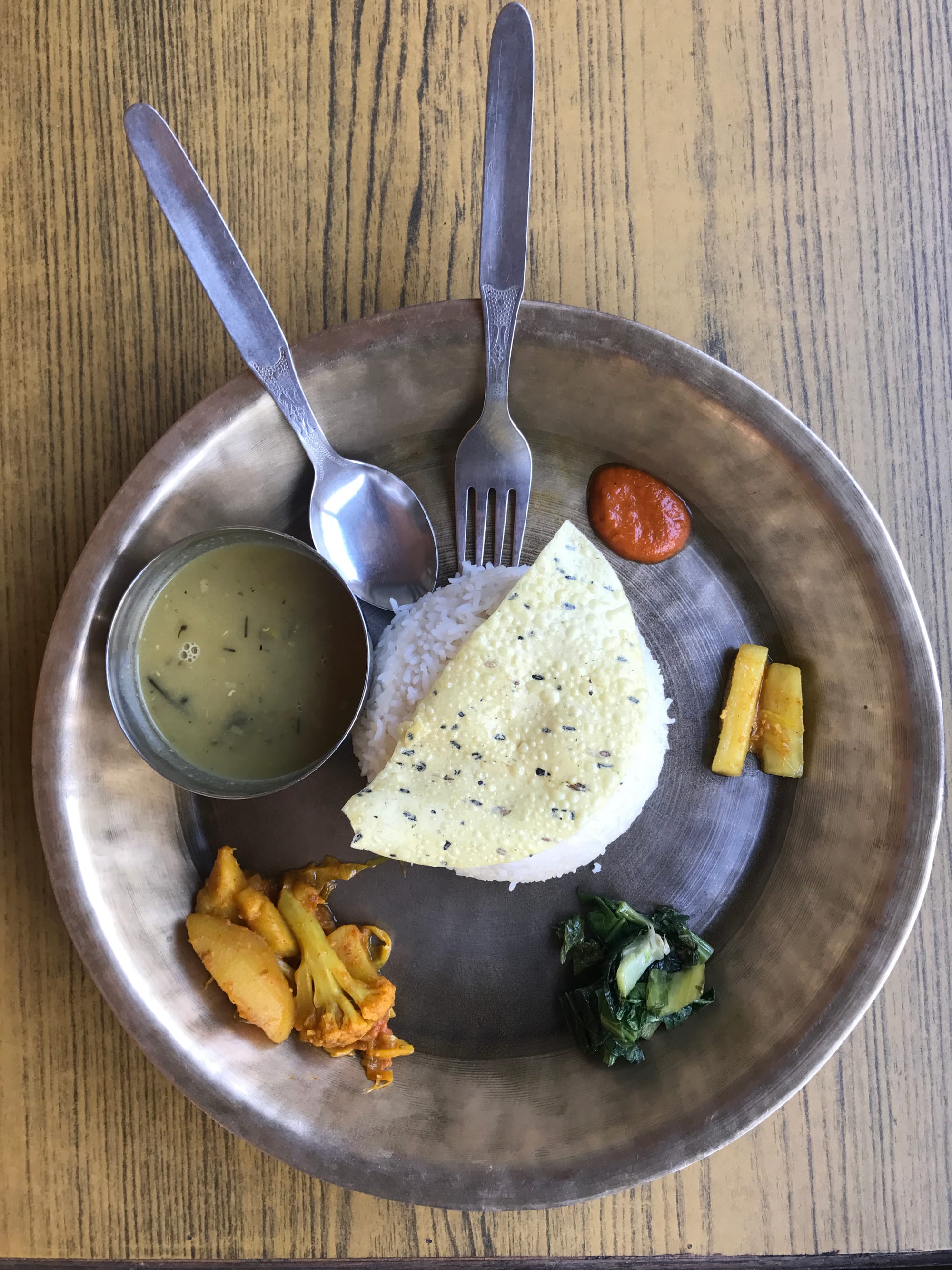 A plate of rice, lentil soup, vegetable curry and pickle