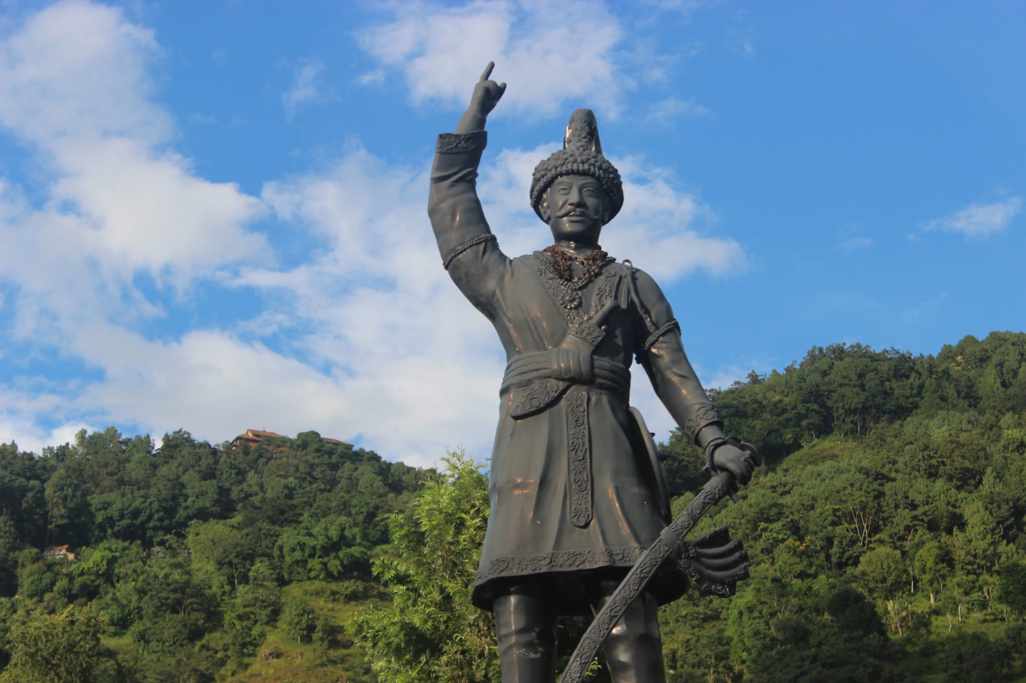 A statue of King Prithvi Narayan Shah pointing forward, in traditional dress and crown
