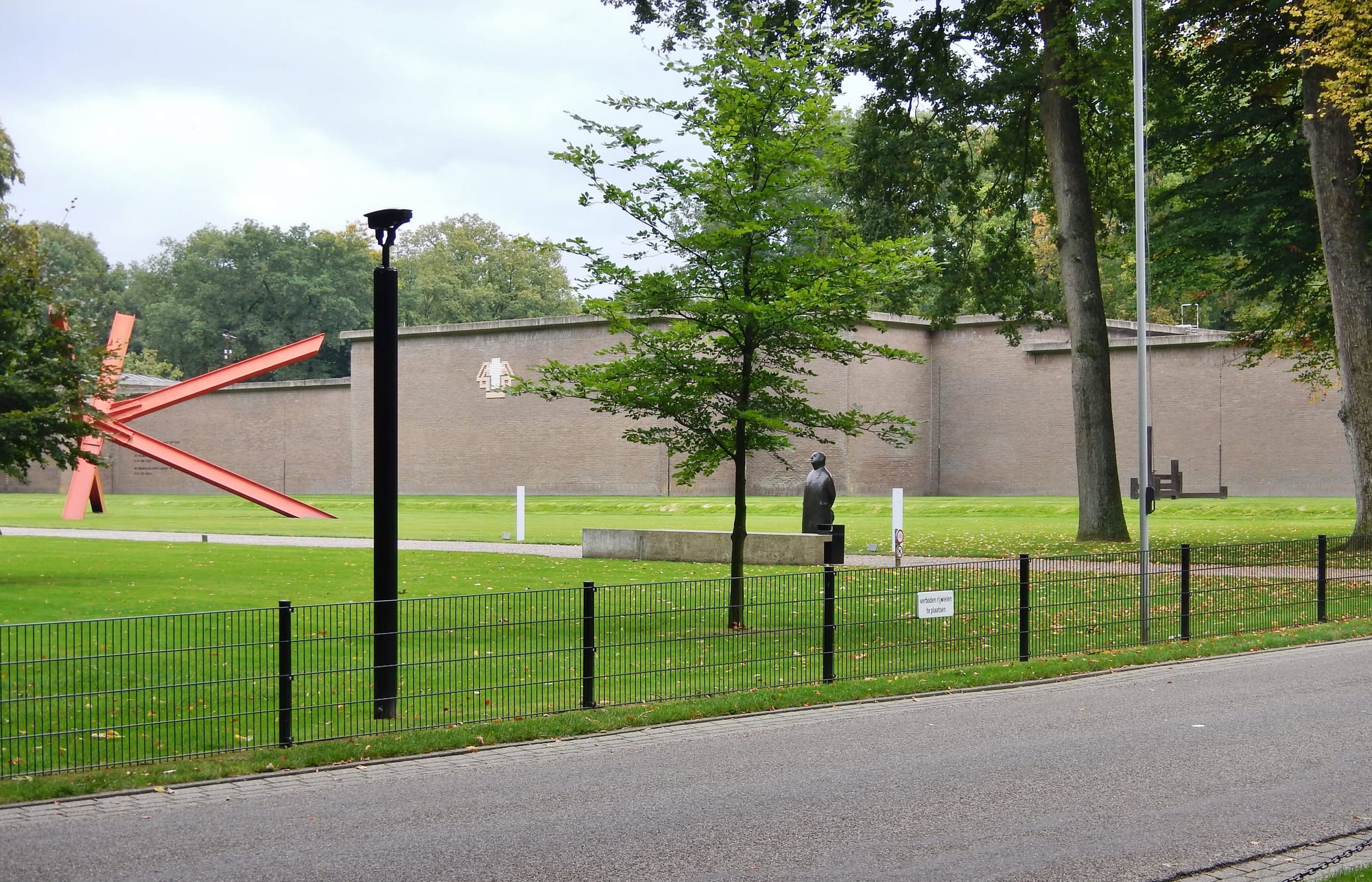 Modern sculptures on a lawn beside a museum building in a forest park
