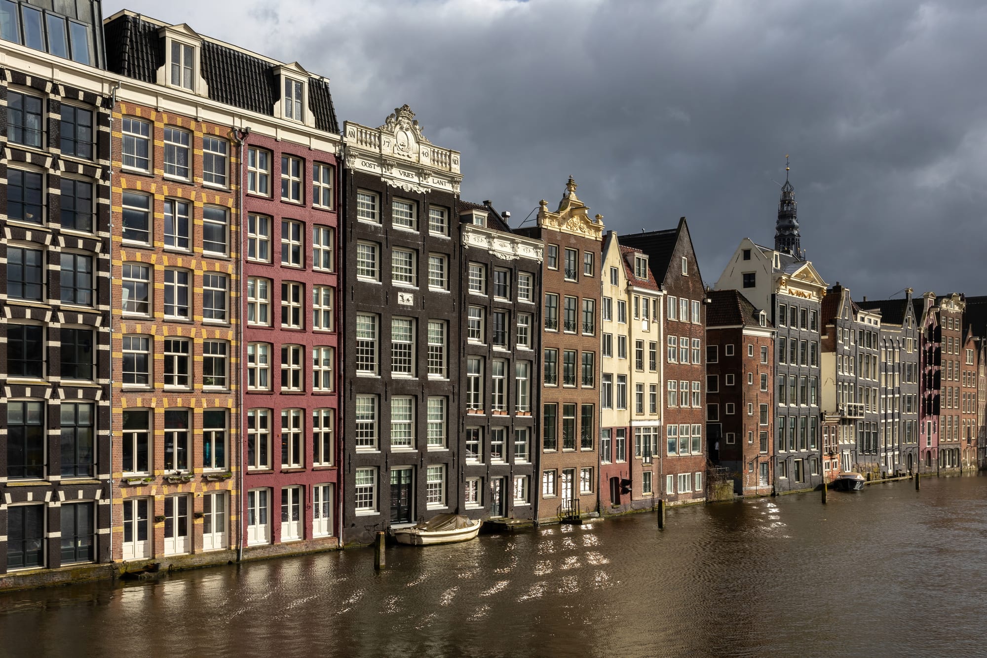 Narrow, colourful gabled canal houses reflected in still water at golden hour
