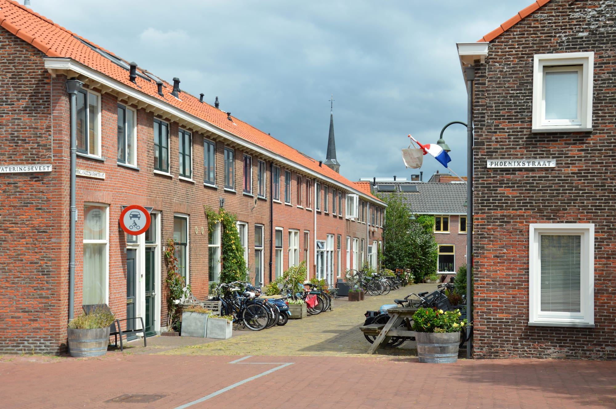 A street of red-brick terraced houses with tiled roofs in Delft, bicycles parked along the pavement outside