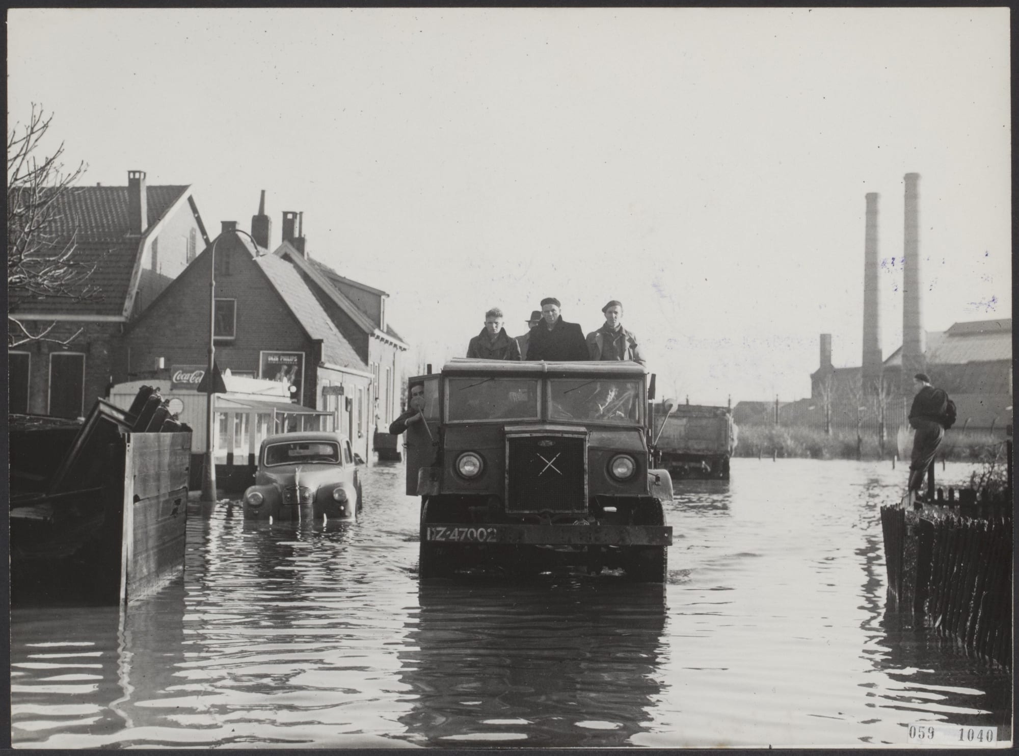 A flooded Dutch landscape in 1953 with a farmhouse and trees standing in a sheet of water