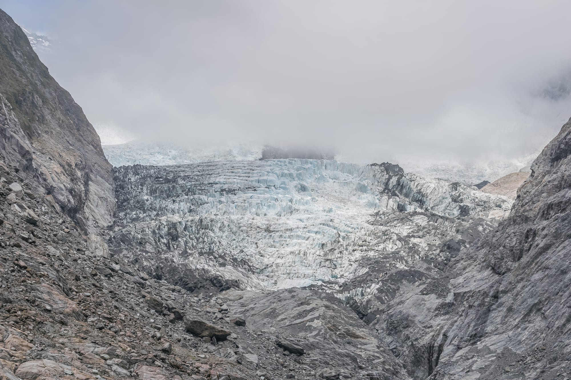 A river of ice flowing between steep valley walls covered in rainforest