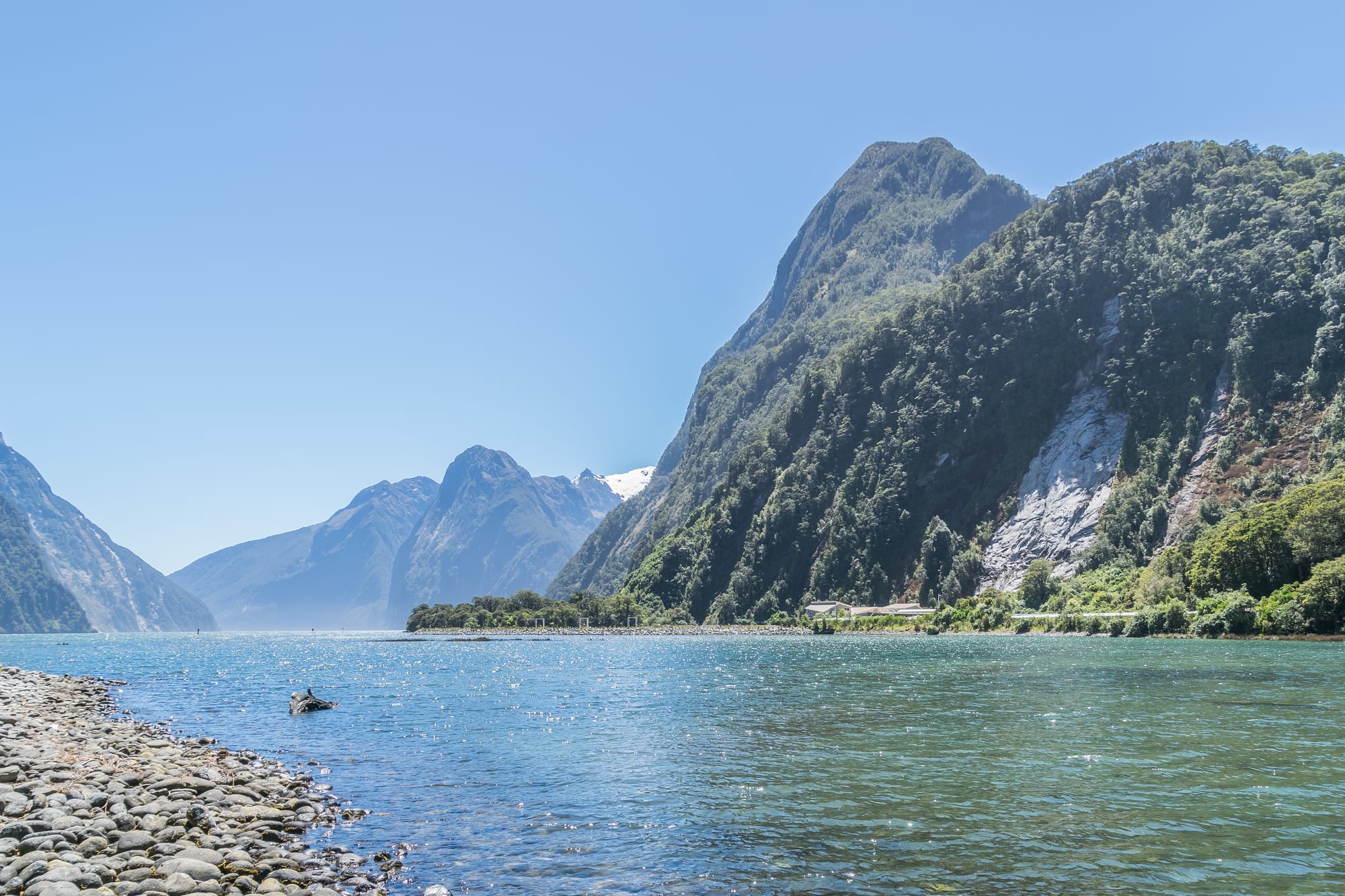 A steep-sided fjord with sheer rock walls and waterfalls dropping into dark water