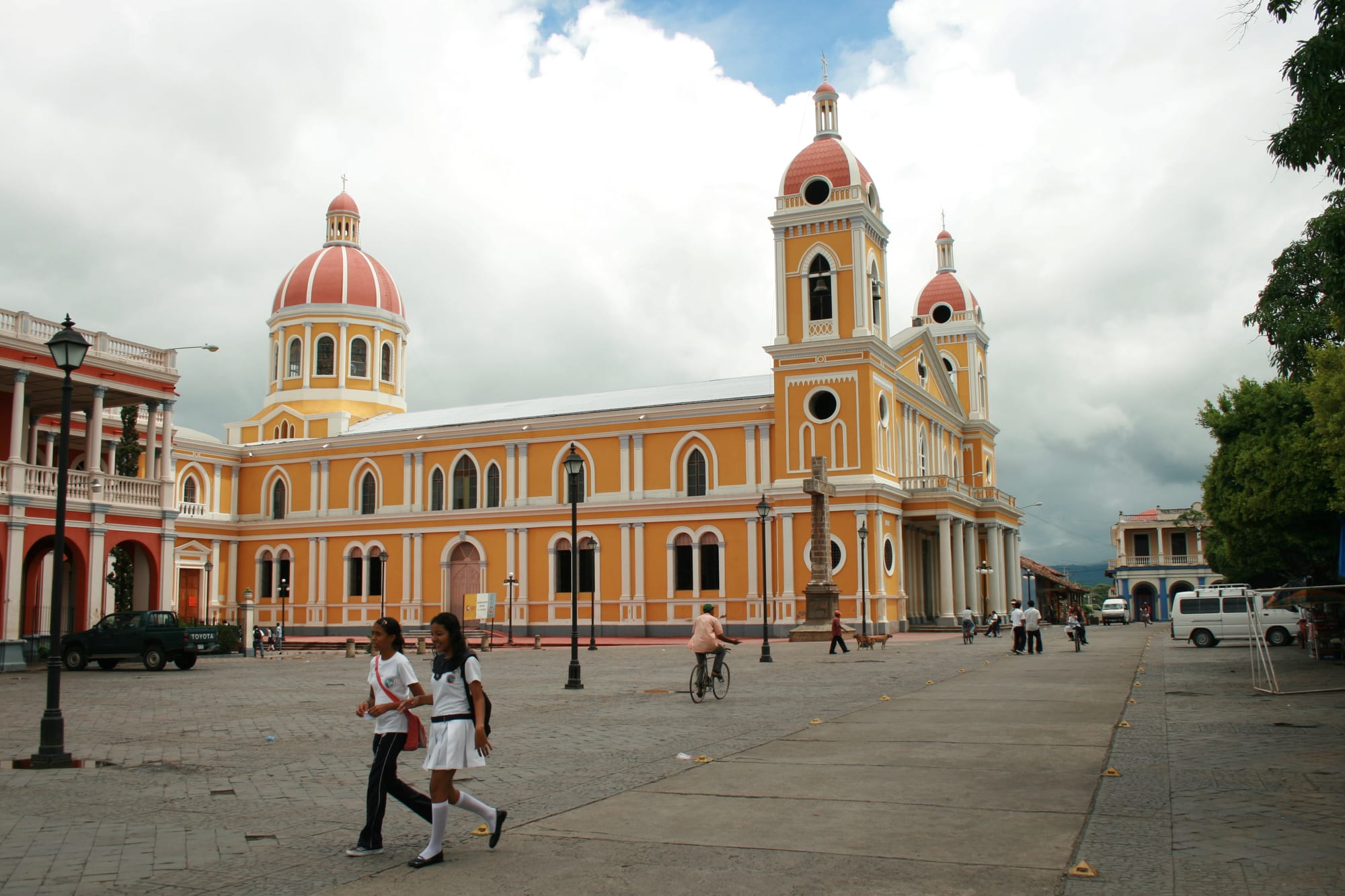 A yellow colonial cathedral with twin towers on a palm-lined square