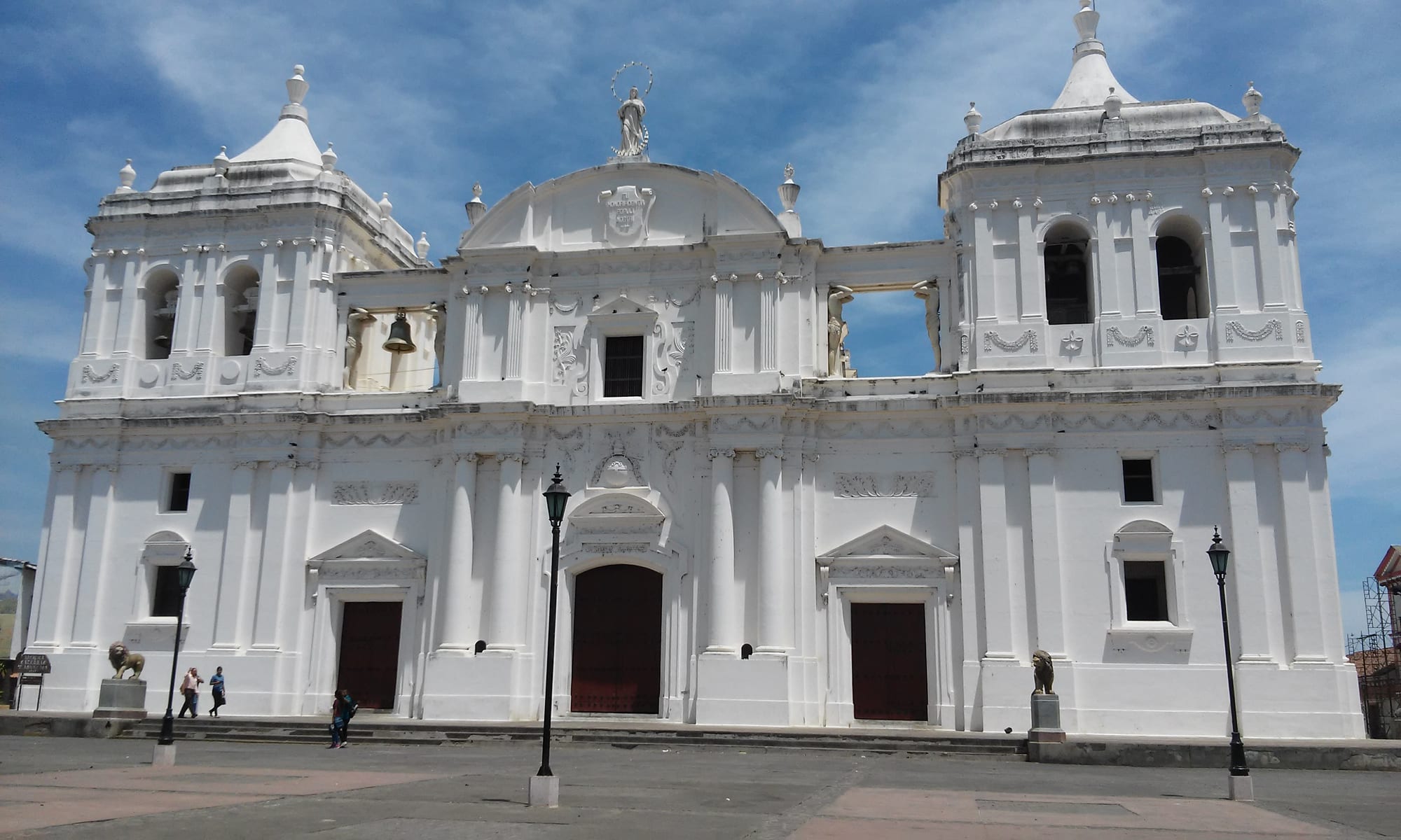 A large white neoclassical cathedral with domes and towers under a bright blue sky