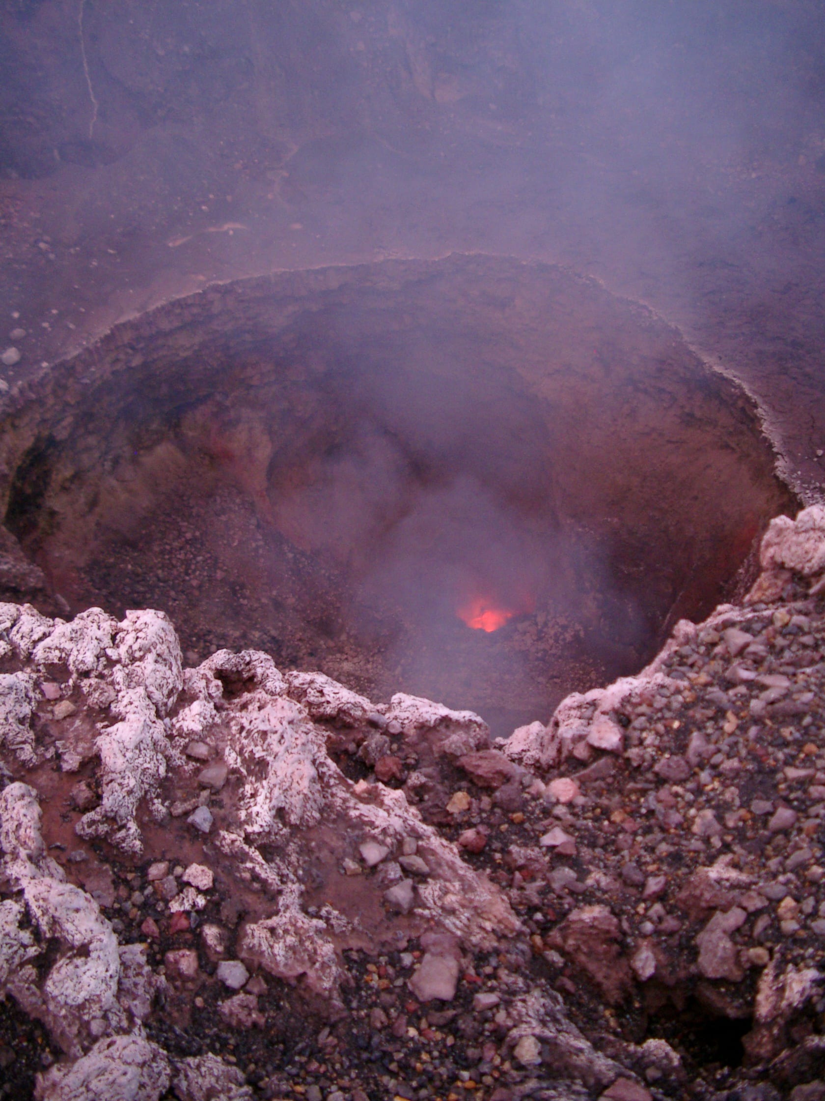 A smoking volcanic crater with a glowing lava lake visible inside