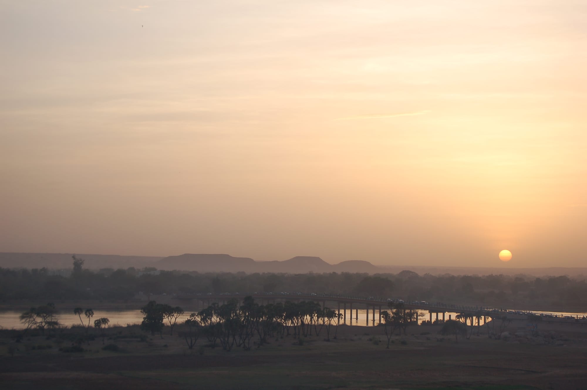The wide, brown Niger River flowing past sandbanks at Niamey under a hazy sky