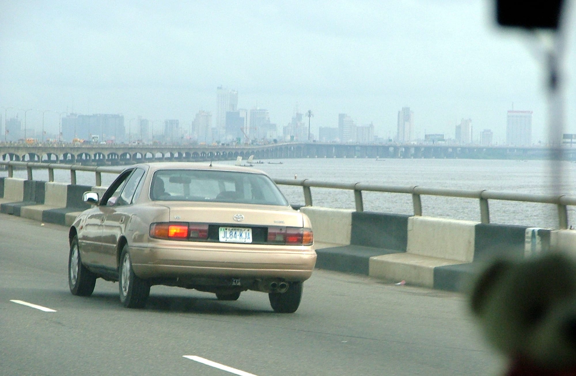 A long bridge crossing a wide lagoon toward a dense city skyline