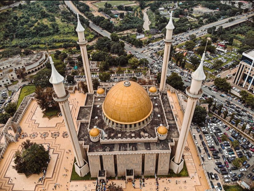 A large modern mosque with a golden dome and four tall minarets