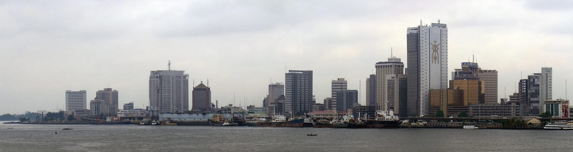 A dense waterfront skyline of high-rise buildings under a hazy sky