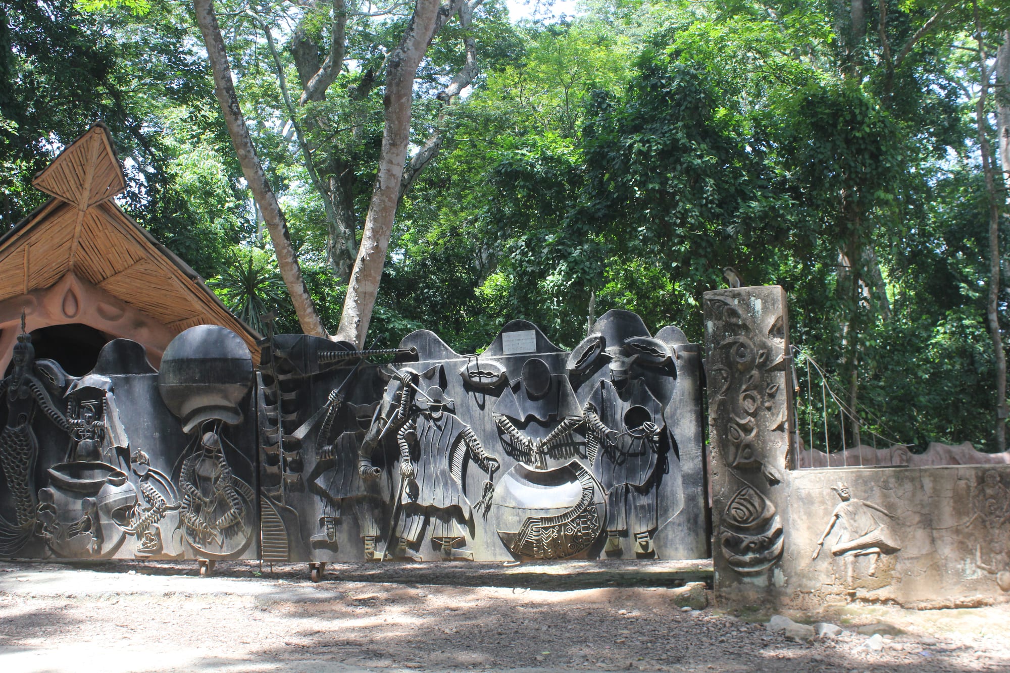 A carved stone gateway leading into a dense sacred forest