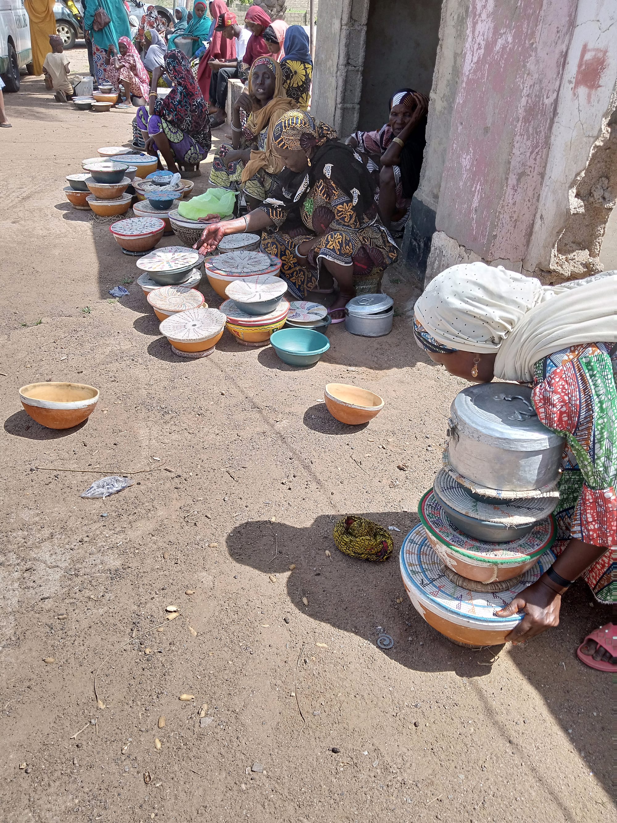 Fulani women in patterned headscarves selling covered bowls of fresh milk by the roadside near Kano