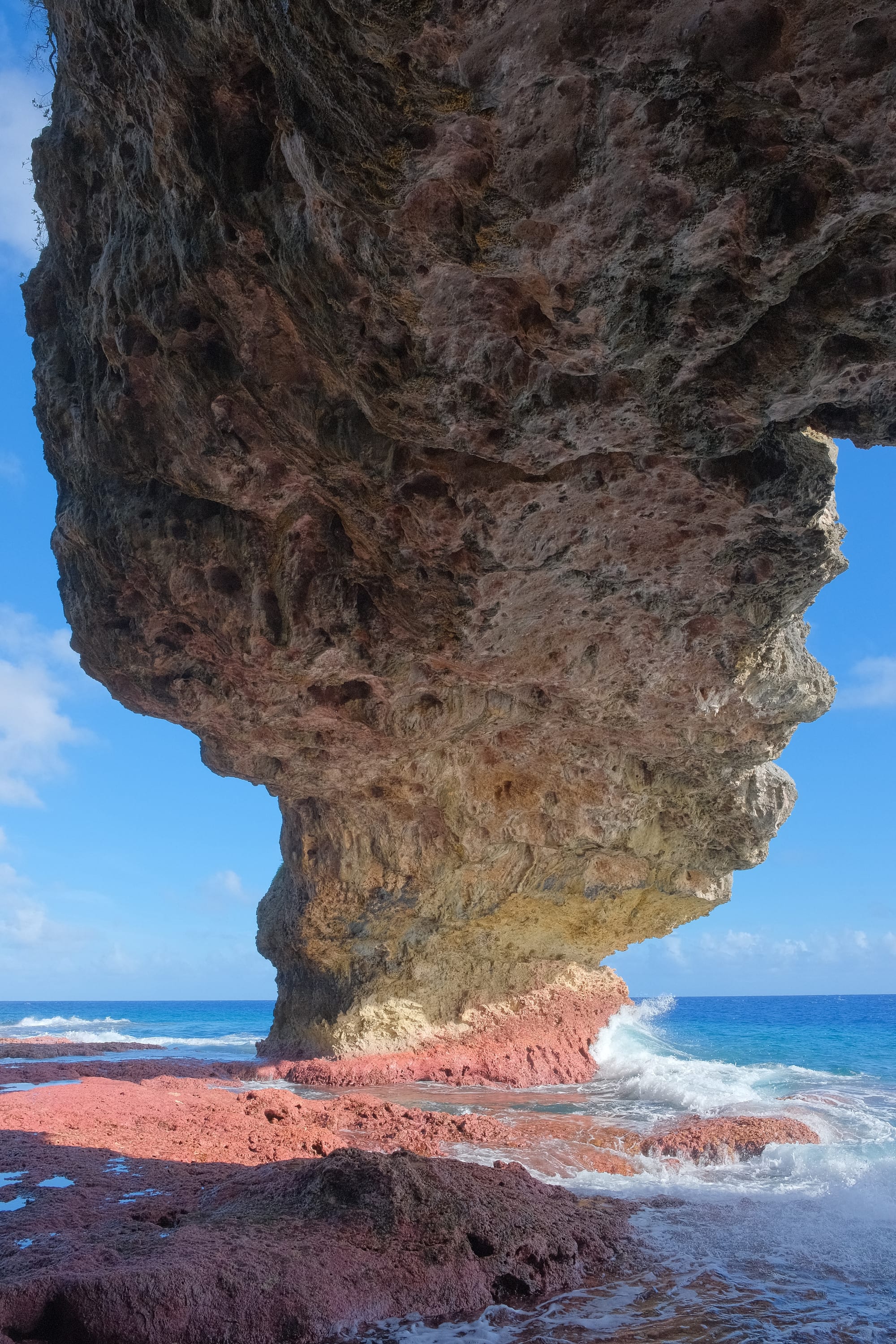 Looking up through the centre of a large natural rock arch toward the sky