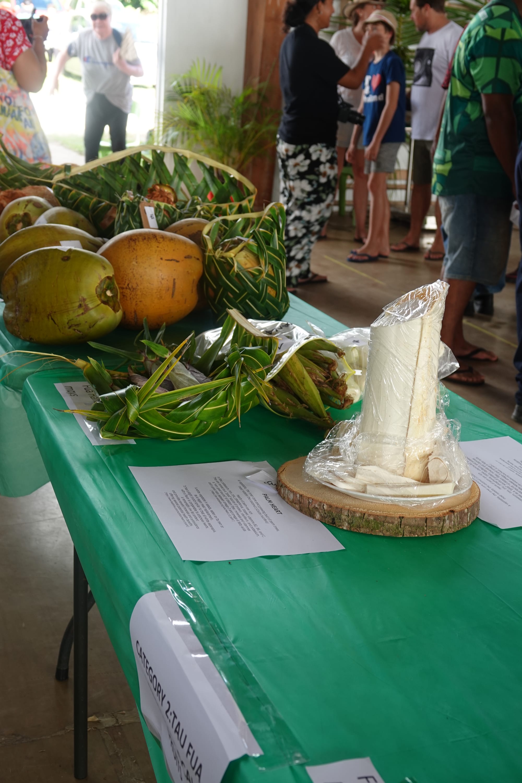 Coconuts, produce and wrapped food entries displayed on a table at a festival
