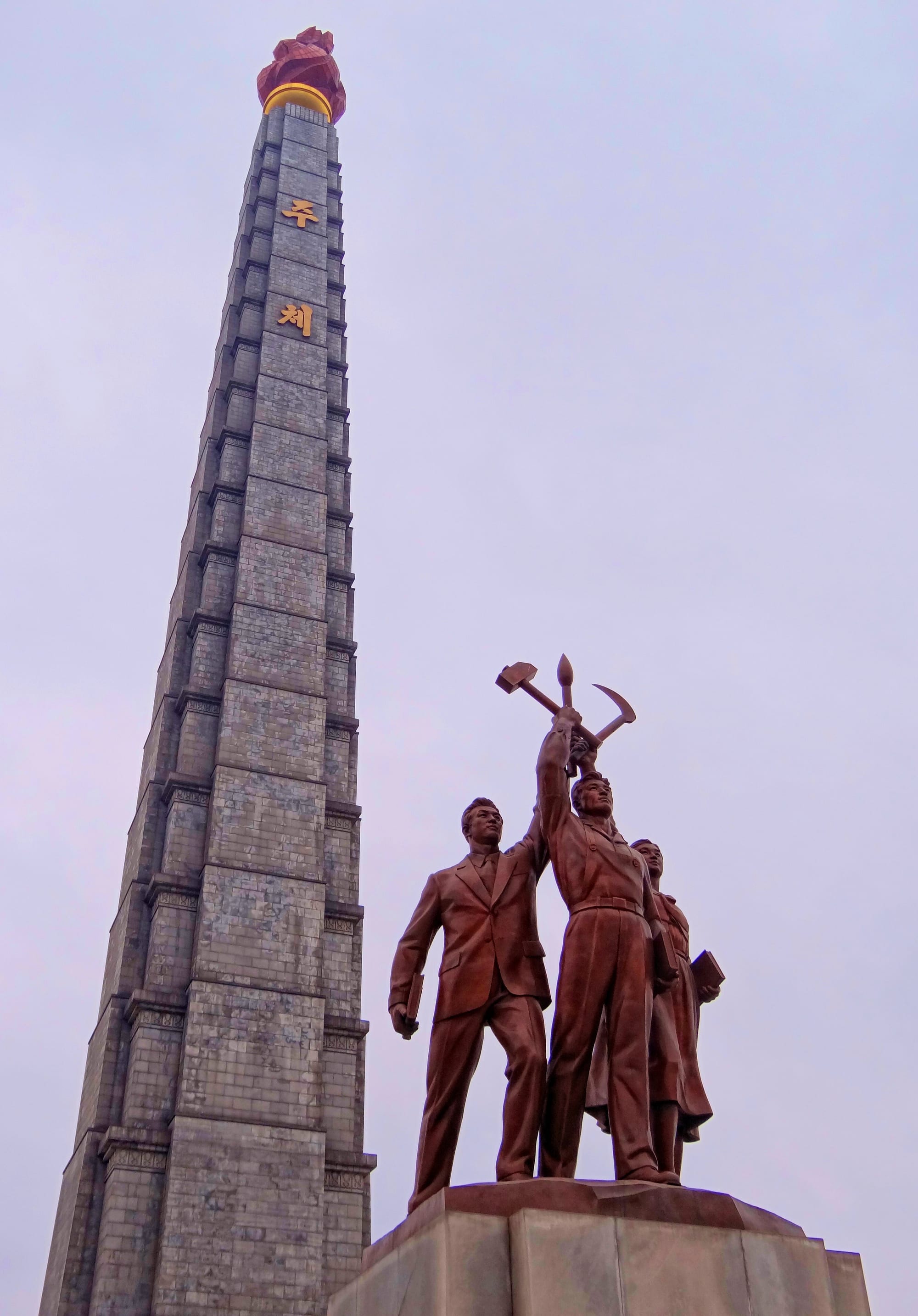A tall stone tower topped with a red illuminated torch-shaped flame