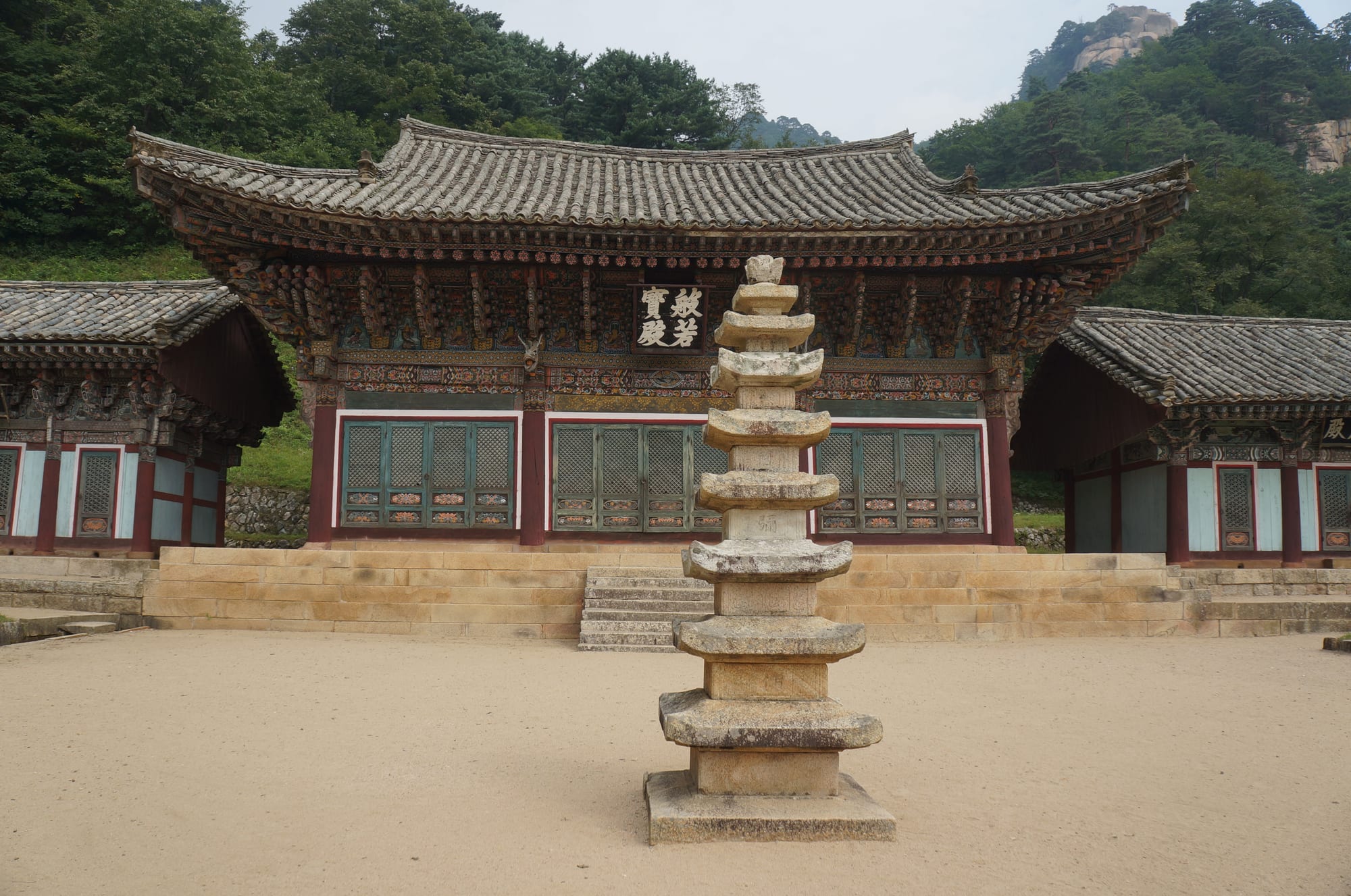 A traditional Korean temple building set against dramatic jagged granite mountains