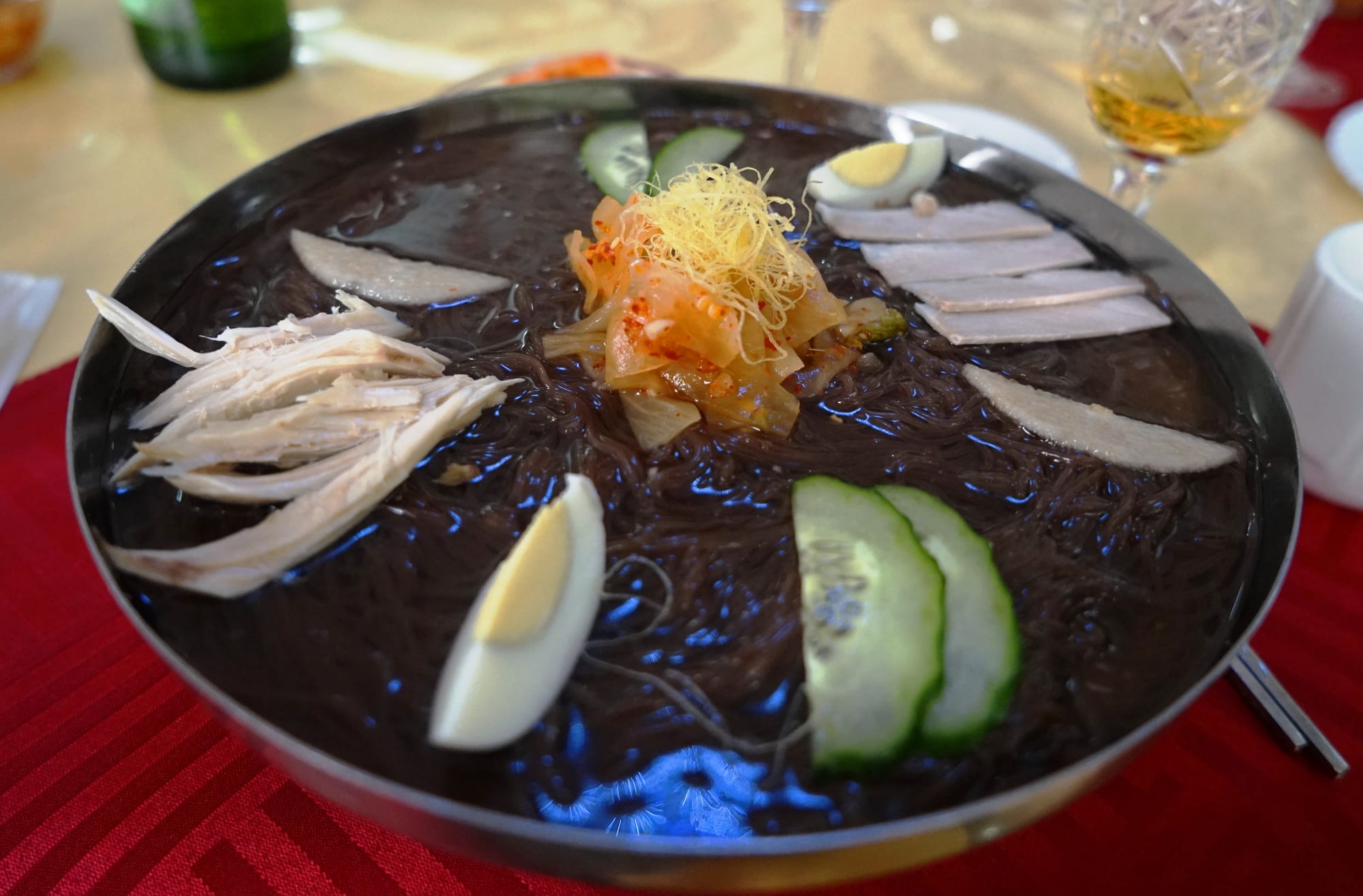 A bowl of cold buckwheat noodles in broth with garnishes