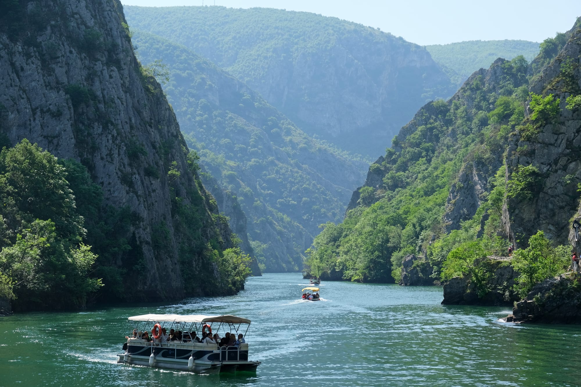 A narrow river canyon with steep forested cliffs and a small lake